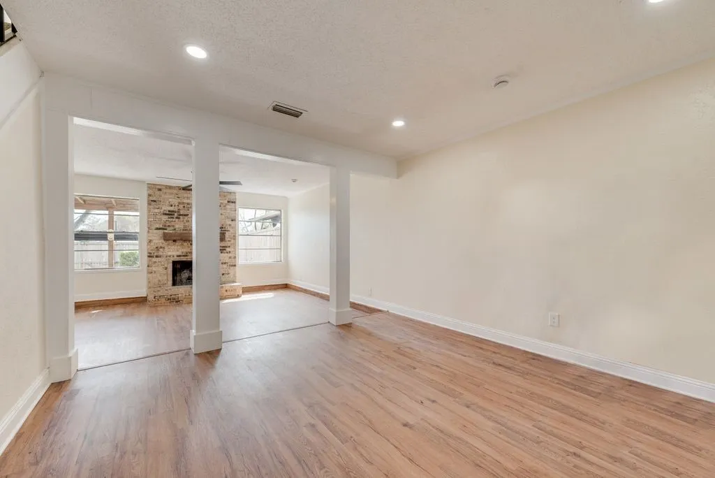 Spacious interior featuring wood-finish flooring, recessed lighting, and a brick fireplace with a wood mantle