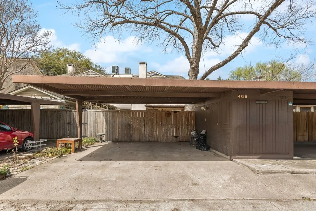 Covered carport with concrete flooring, wood-paneled exterior, and address numbers 4816