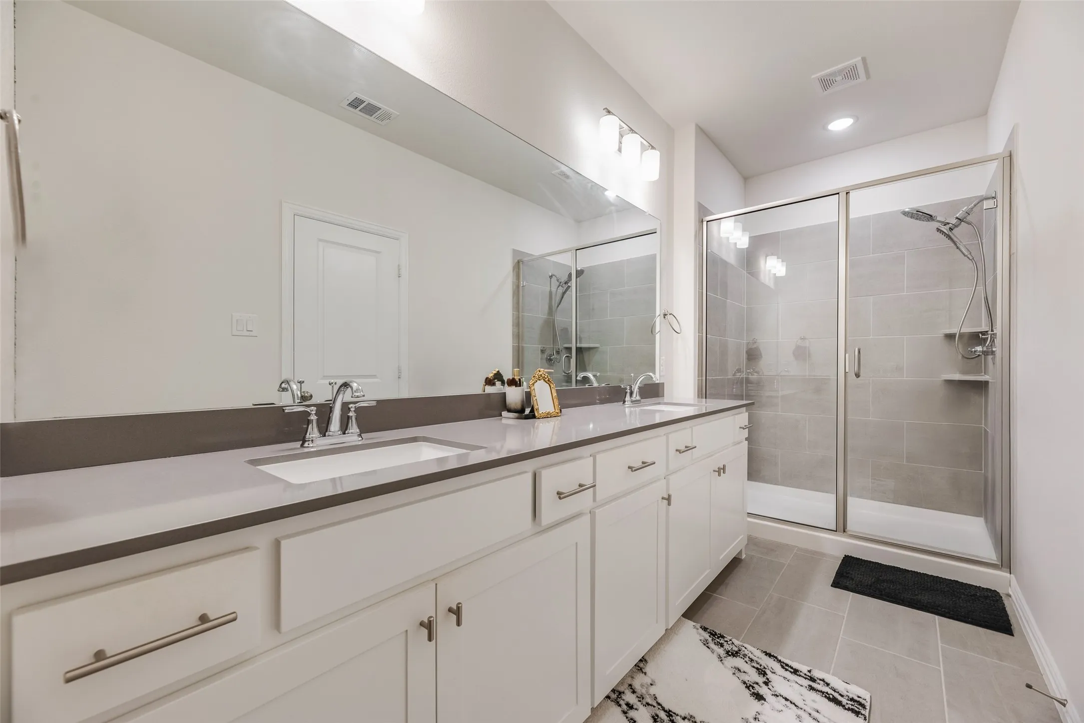 Dual vanity with undermount sinks, gray countertop, and white cabinetry