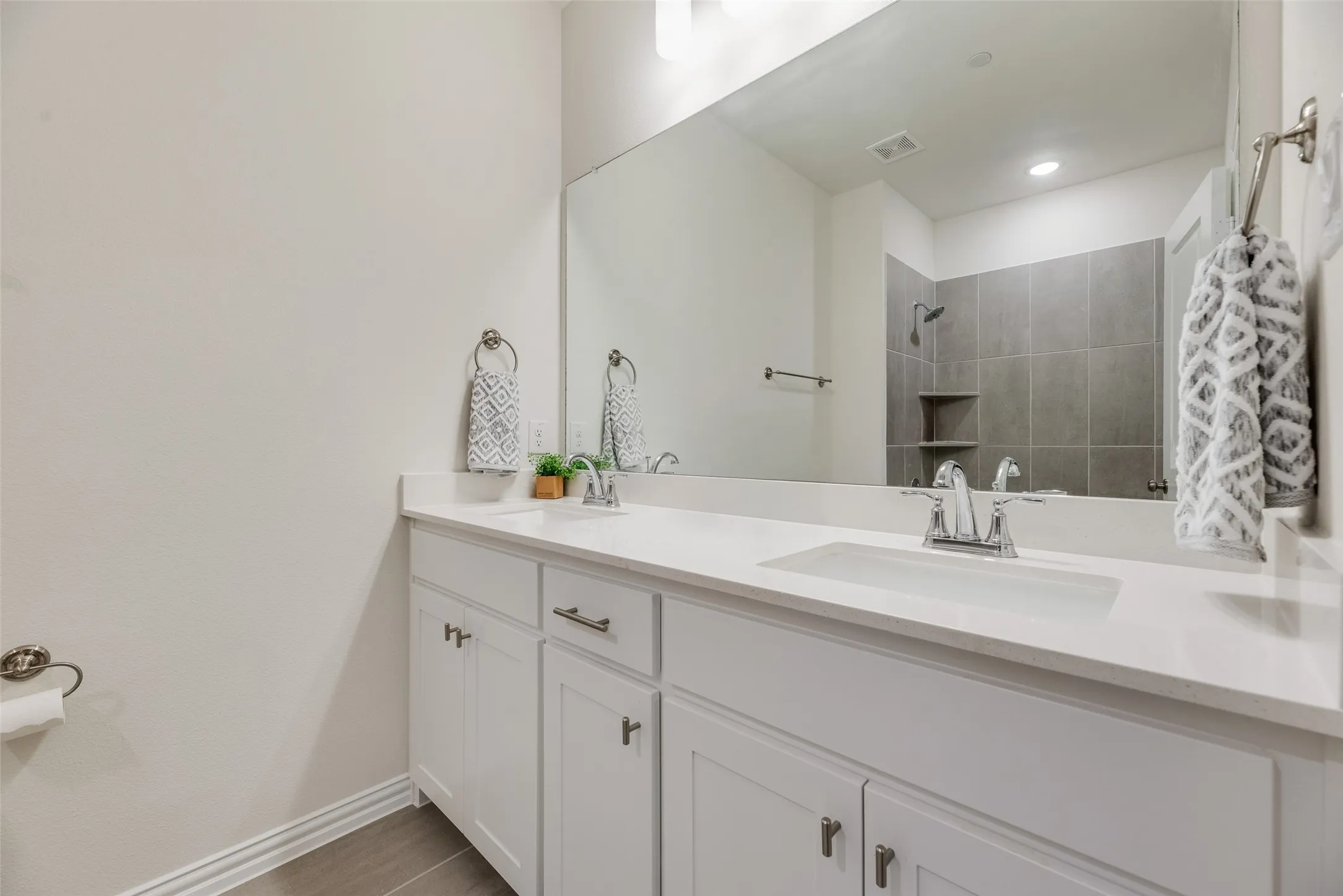 Double vanity with integrated sinks, white cabinetry, and a large wall-mounted mirror