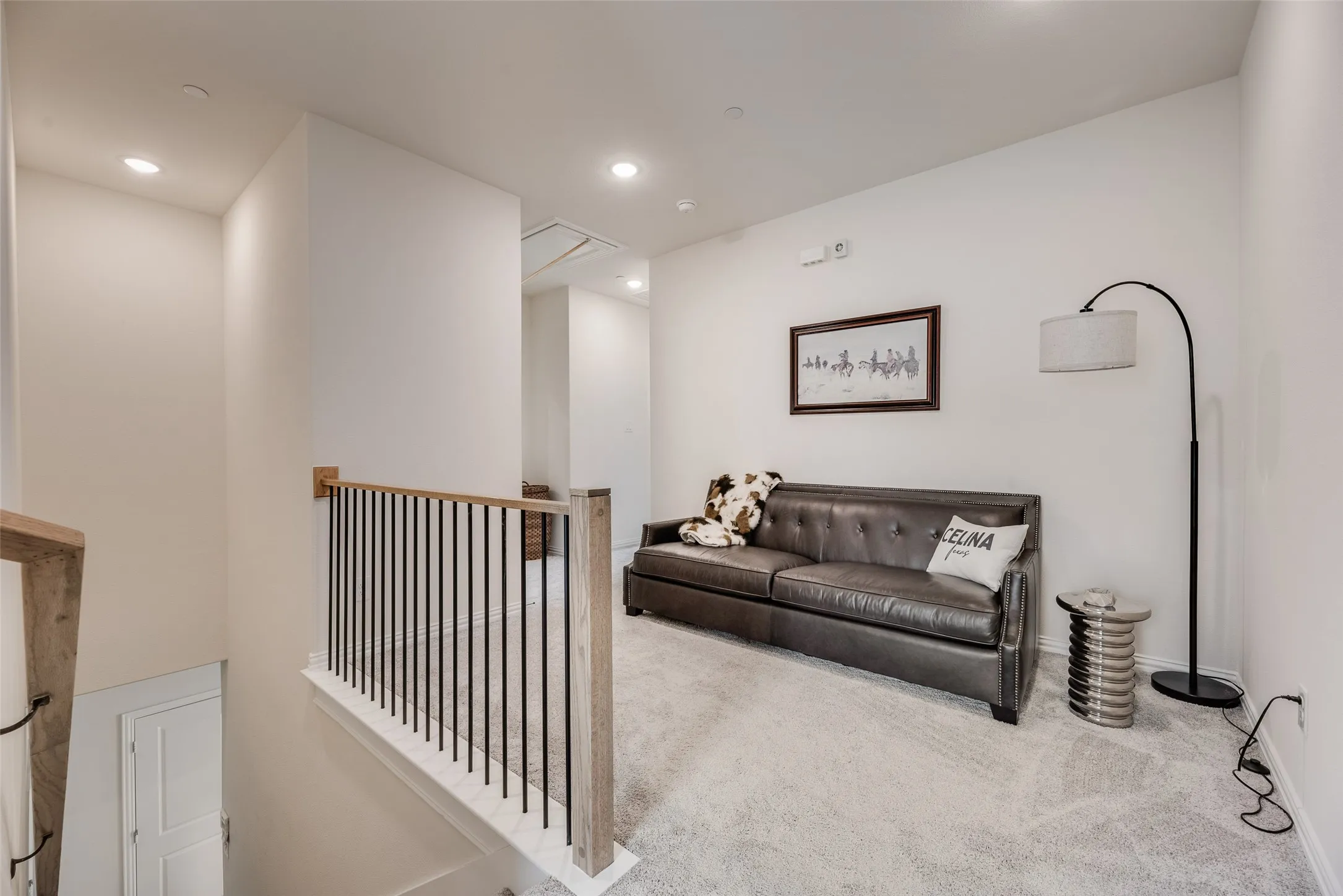 Upper-level gameroom featuring light-toned carpeting, recessed lighting, and a contemporary wood and metal railing system