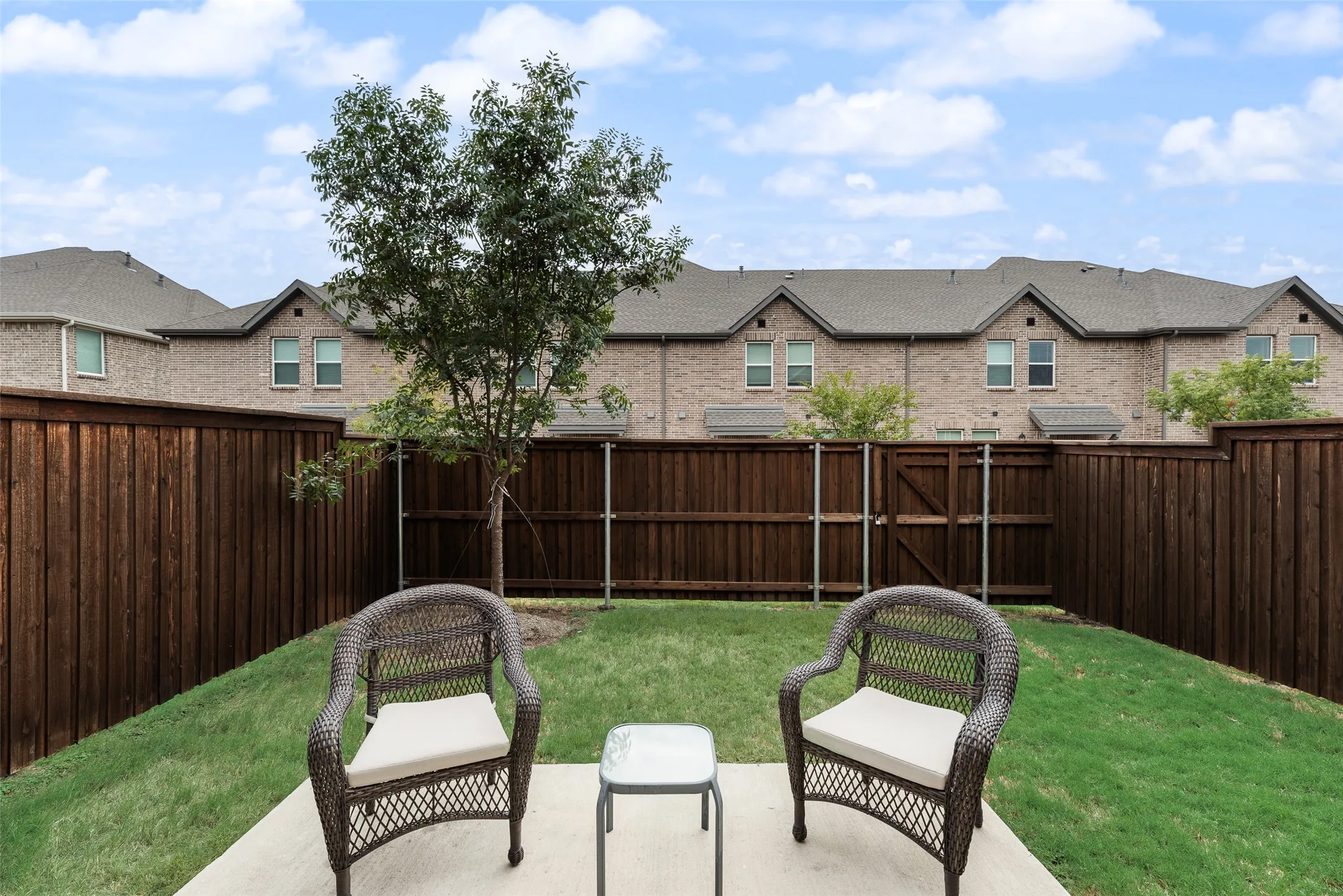 Private backyard with wood fencing, a concrete patio area, and a green lawn