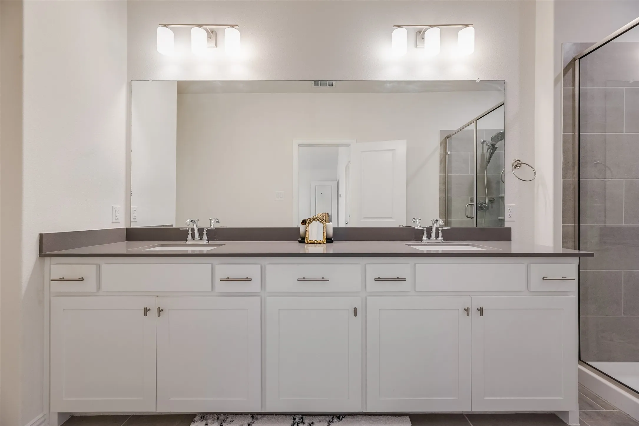 Double vanity with white cabinetry and brushed nickel hardware, set against a dark countertop
