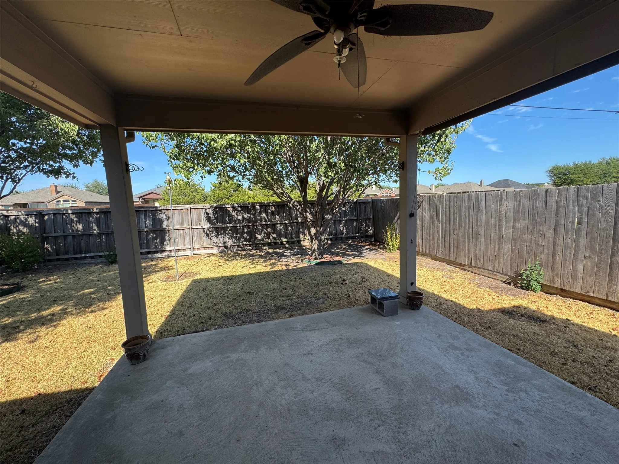 Covered patio with a ceiling fan, concrete surface, and a private wooden fence