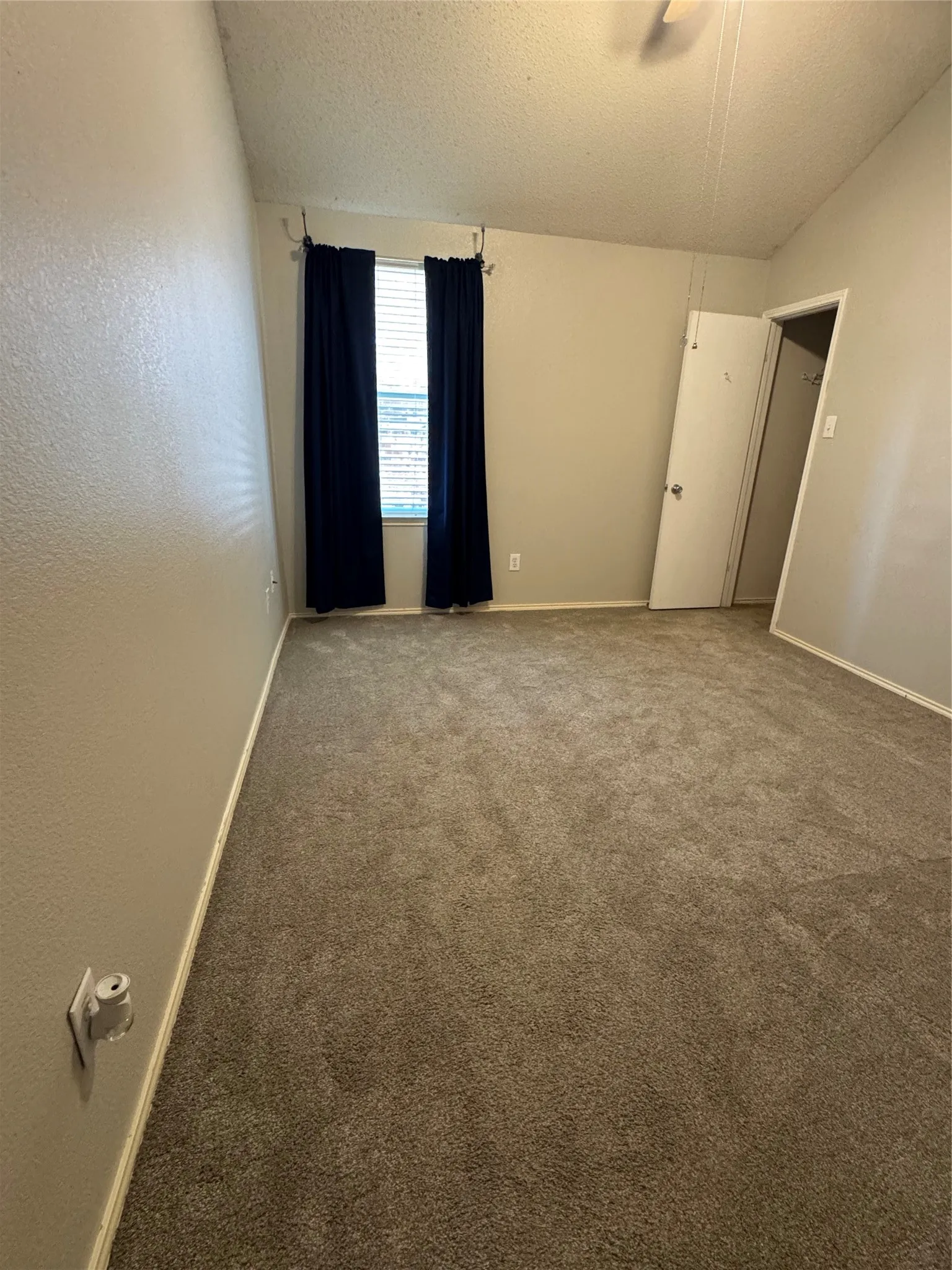 Carpeted flooring, neutral wall tones, window with vertical blinds, and a built-in closet