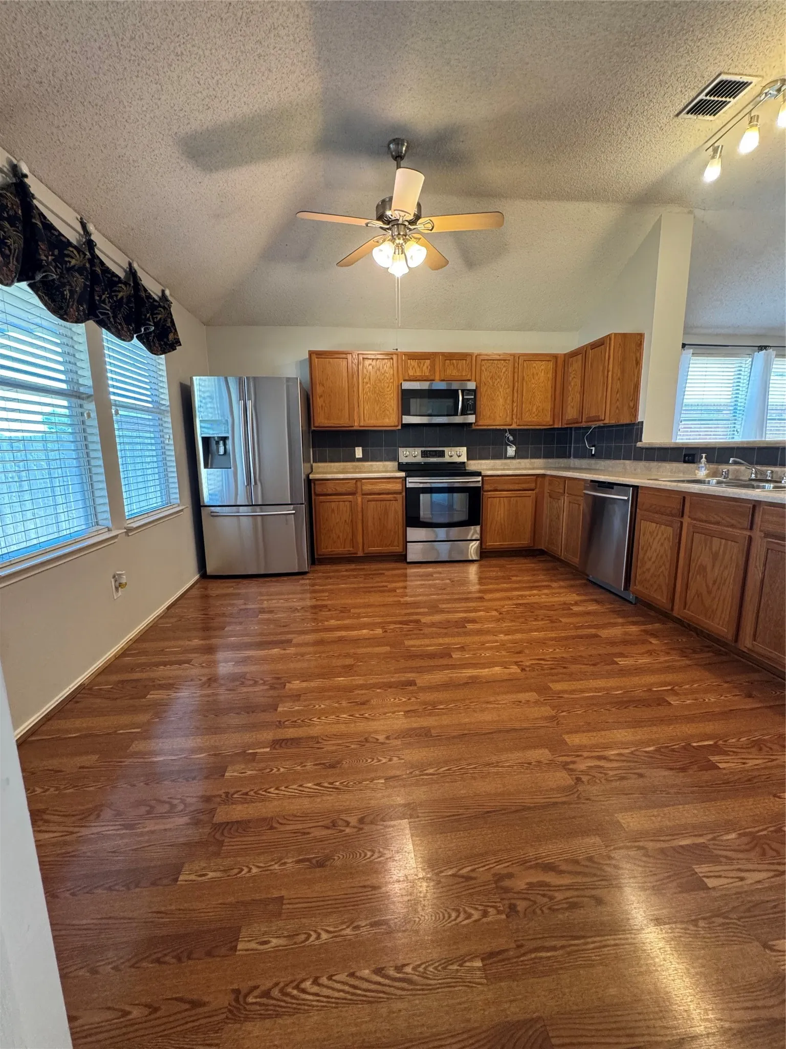 Wood-finish flooring throughout, complemented by wood cabinetry and stainless steel appliances
