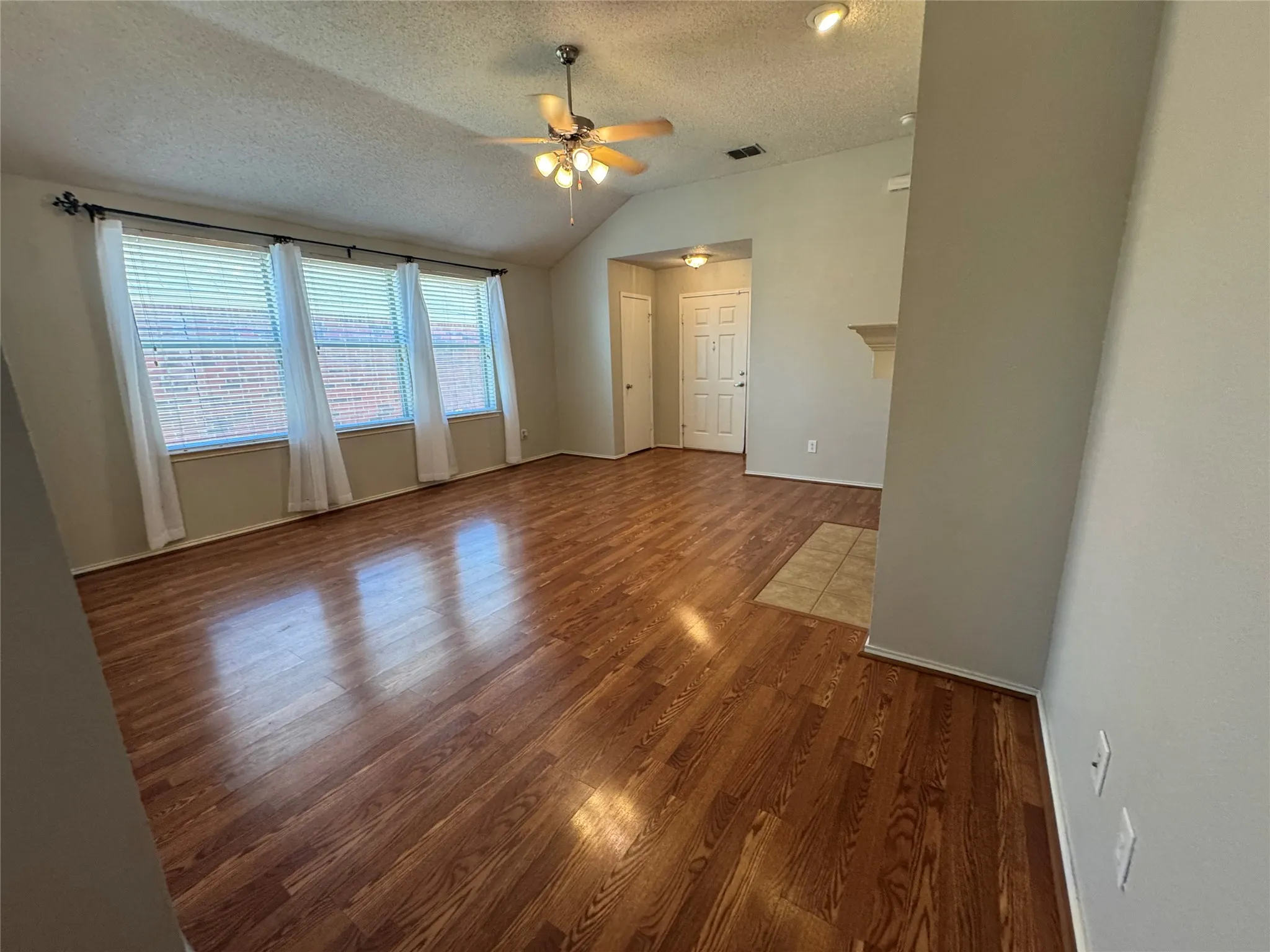 Vaulted ceiling, wood-finish flooring, recessed lighting, ceiling fan, and a built-in mantel