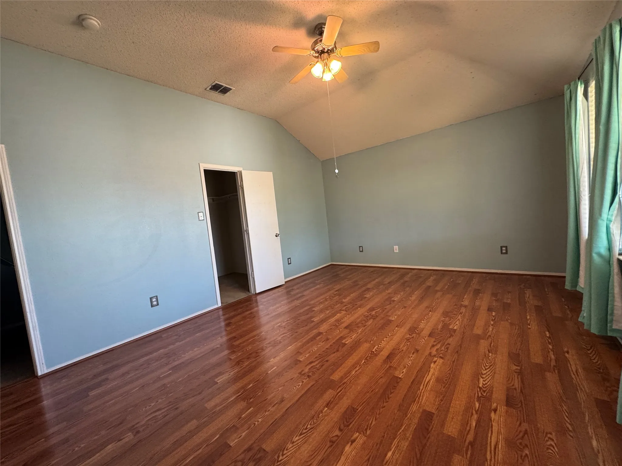 Vaulted ceiling with a ceiling fan, wood-finish flooring, and light blue walls