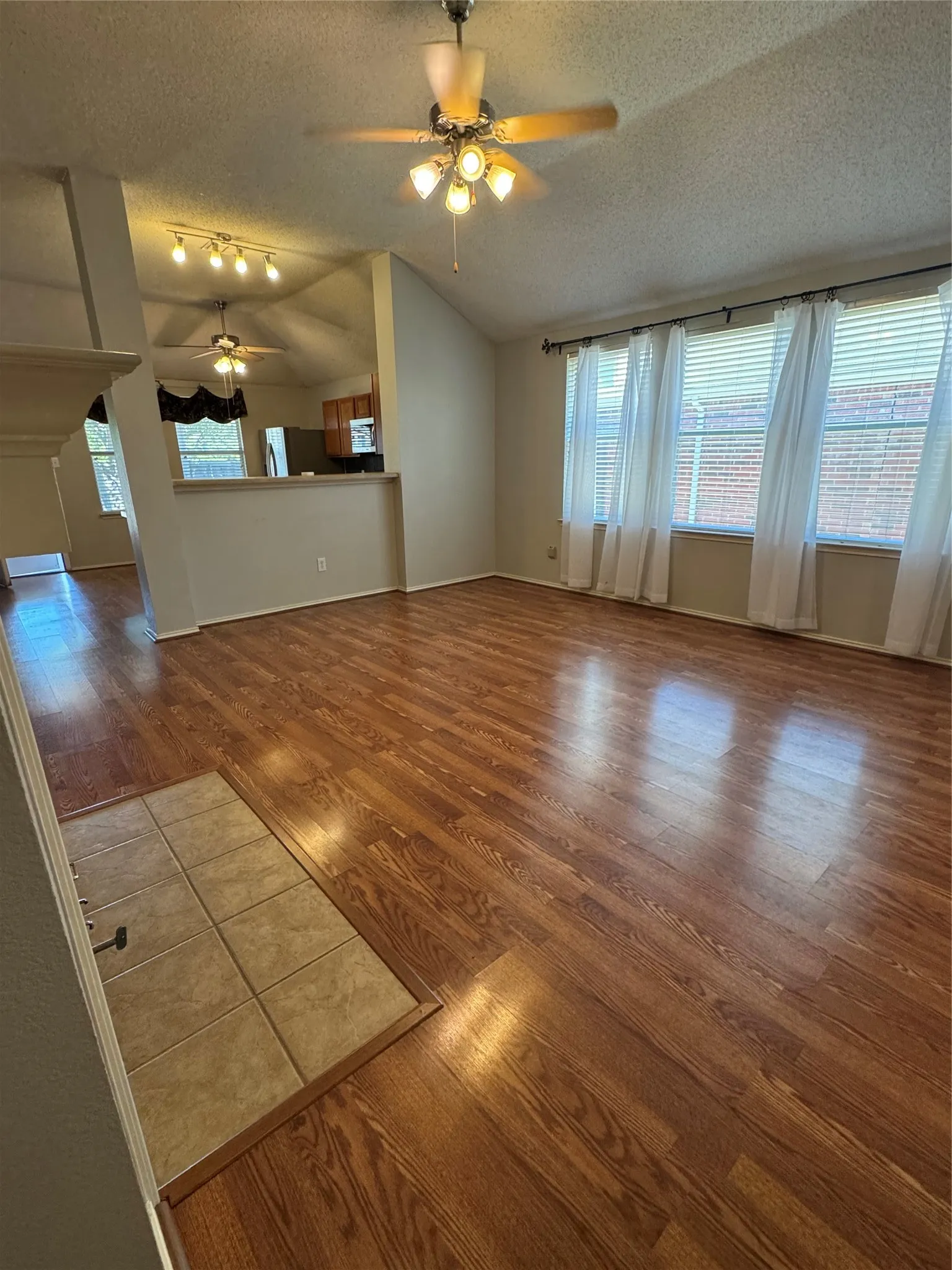 Vaulted ceiling with a ceiling fan, wood-finish flooring, and multiple windows