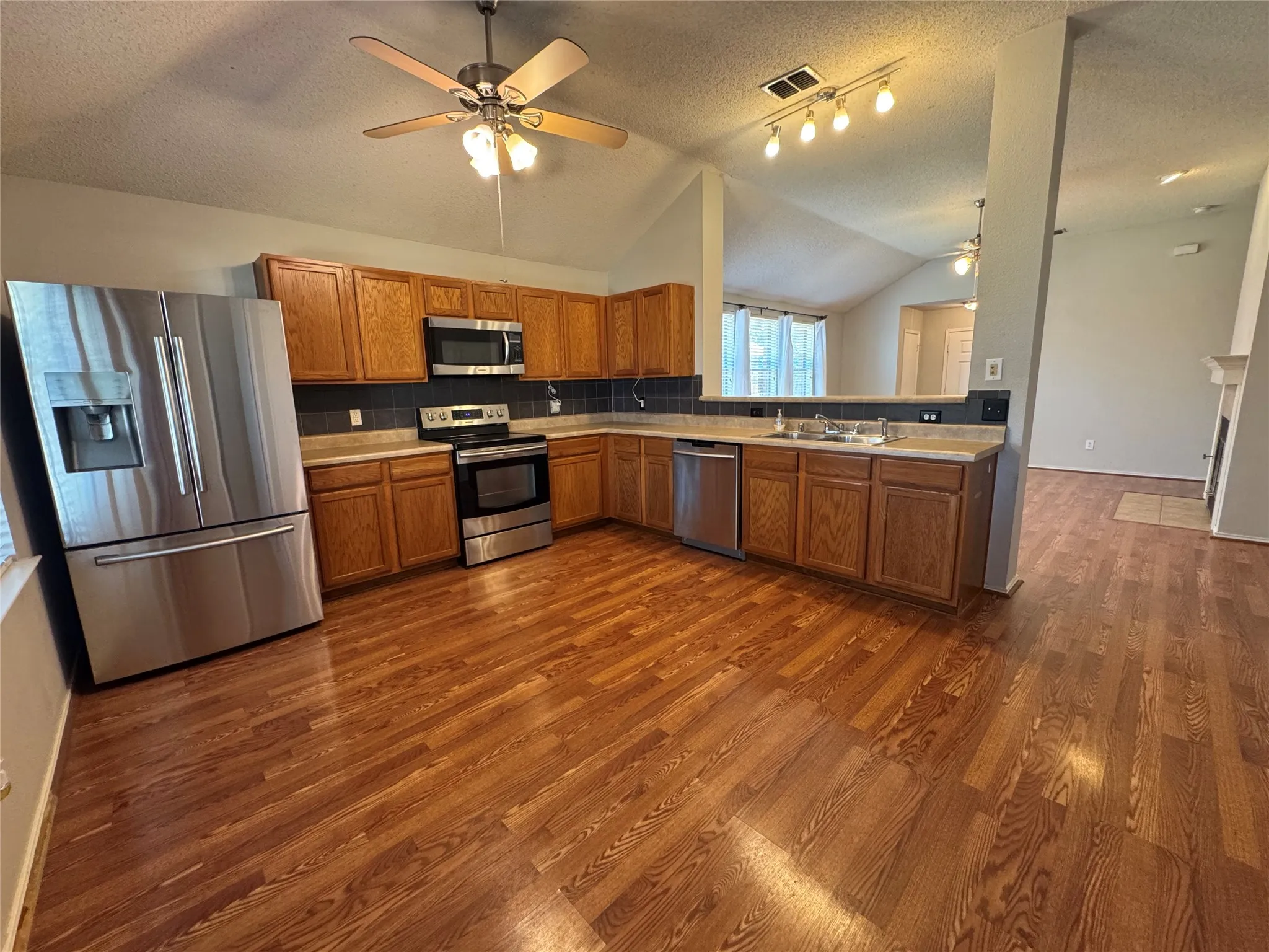 Kitchen featuring wood-finish flooring, stainless steel appliances, wood cabinetry, and track lighting