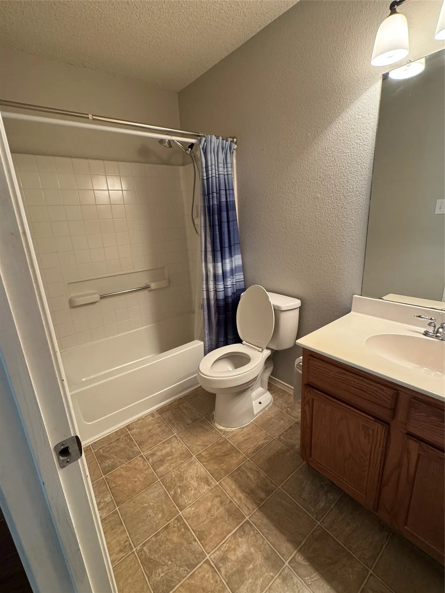 Bathroom featuring a white tub and shower combination with tile surround, a single vanity with an integrated sink, and wood-finish cabinetry