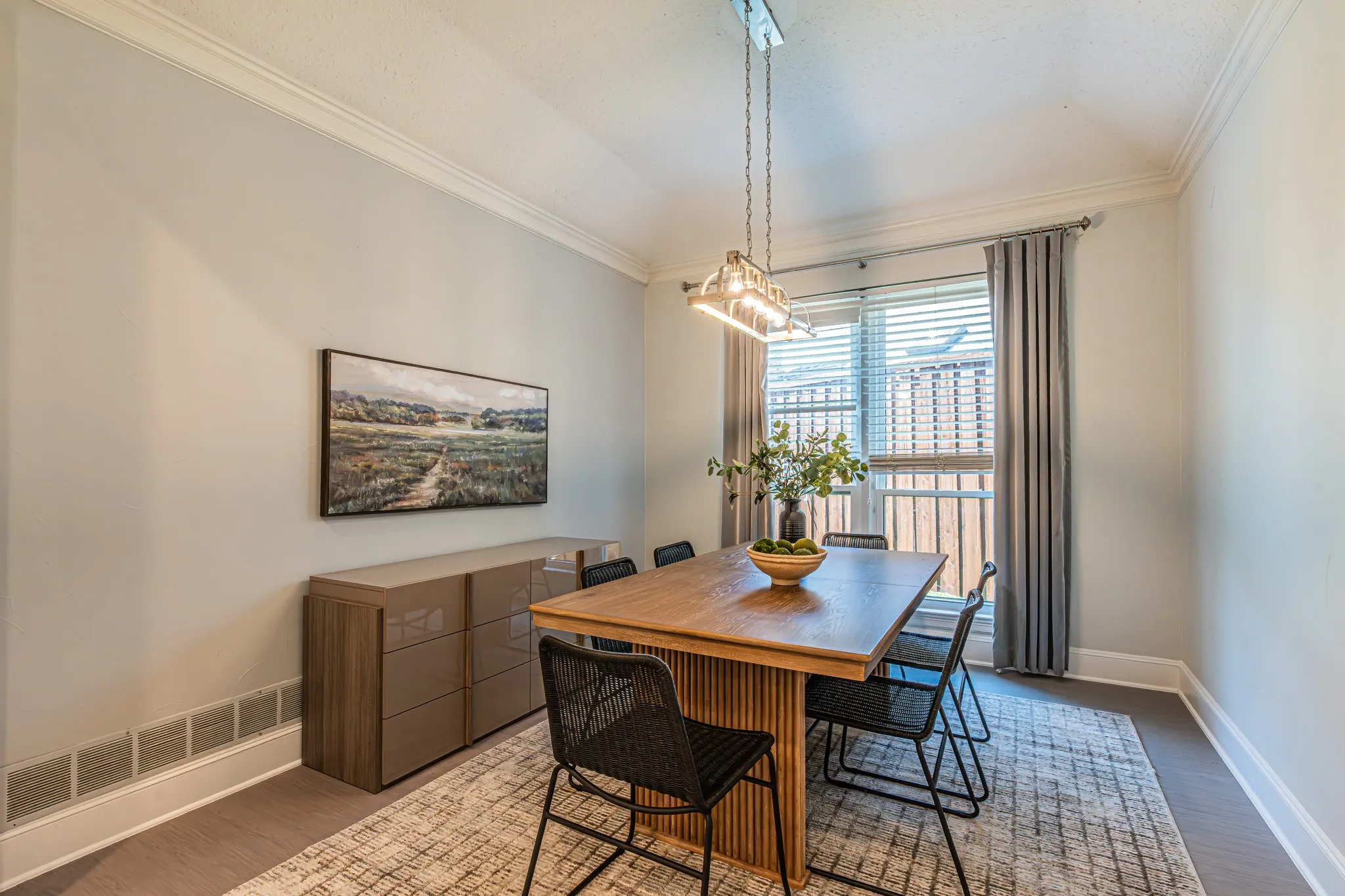 Crown molding, wood-finish flooring, contemporary chandelier, large window with blinds, and a built-in wall unit