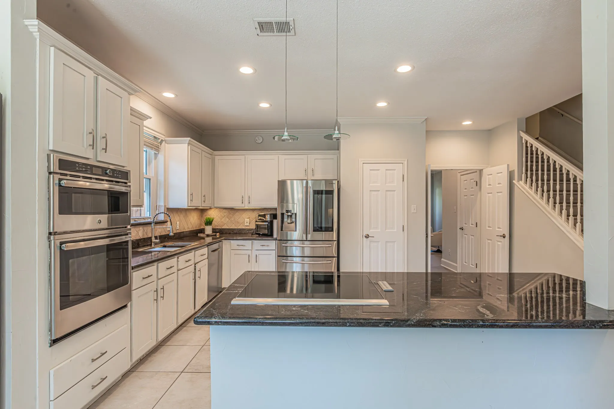 Kitchen featuring white cabinetry, stainless steel appliances, dark countertops, and recessed lighting