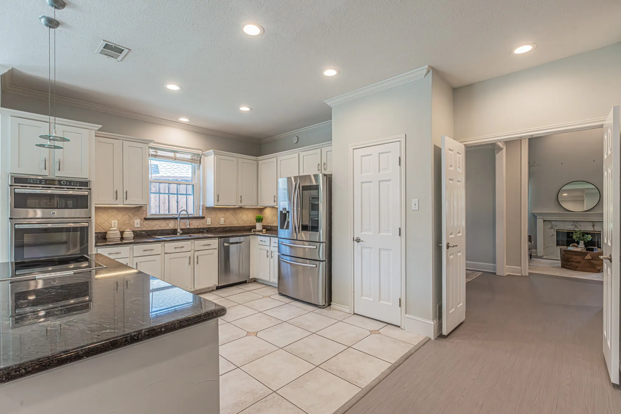 Kitchen featuring stainless steel appliances, granite countertops, white cabinetry, tile flooring, and recessed lighting