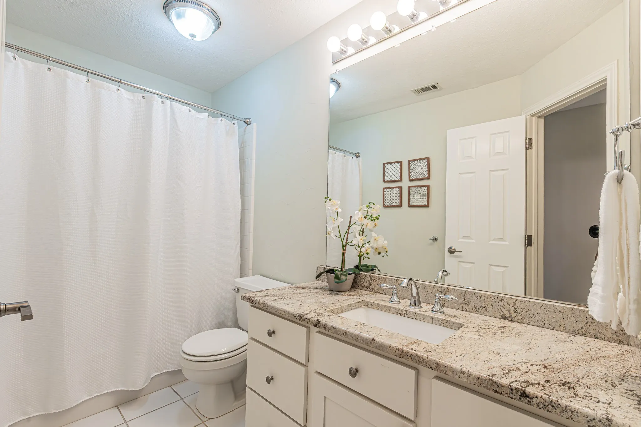Bathroom featuring a vanity with an integrated sink, polished chrome faucet, and a large wall mirror