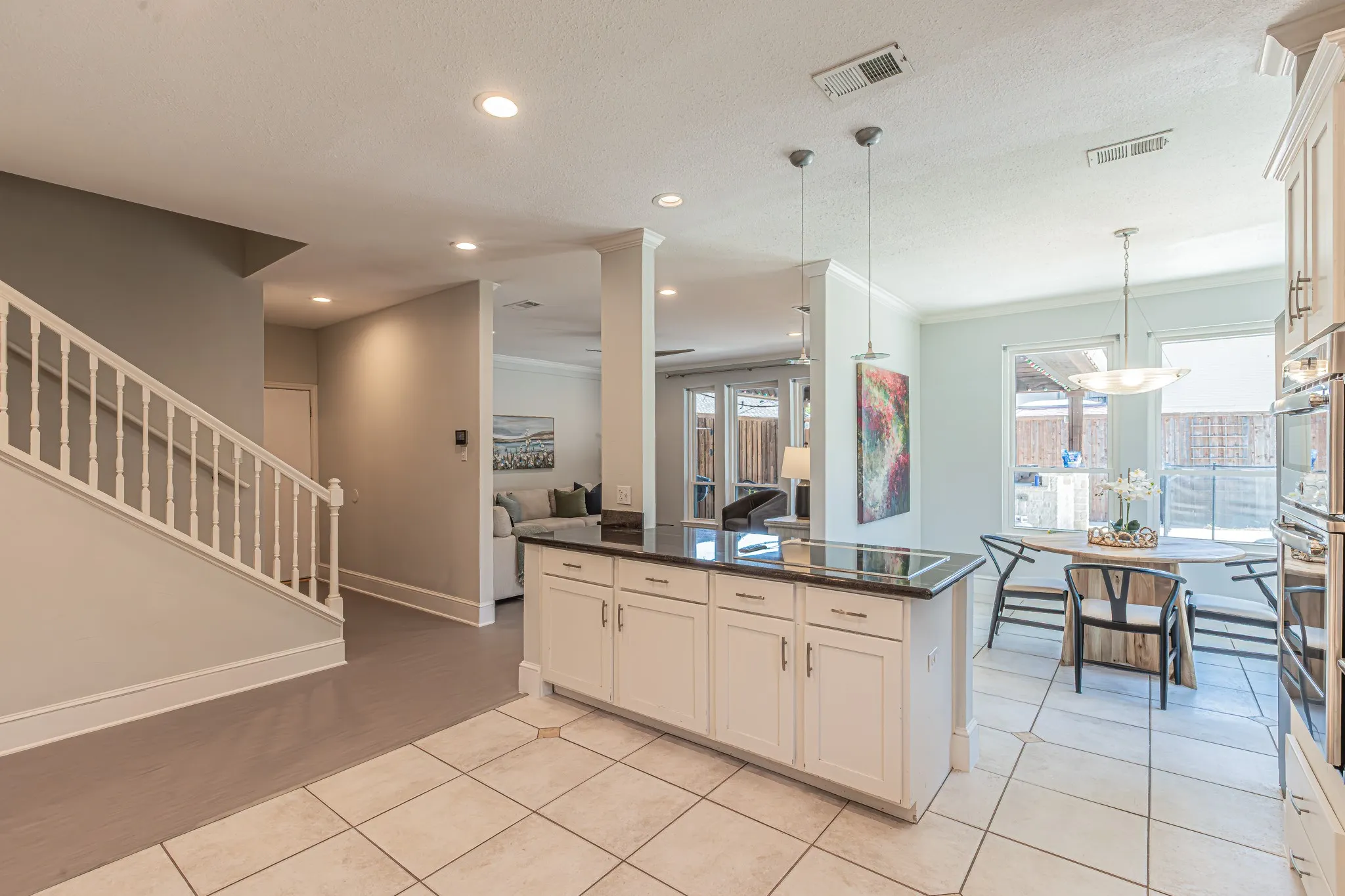 Kitchen island with dark countertop, white cabinetry, and pendant lighting