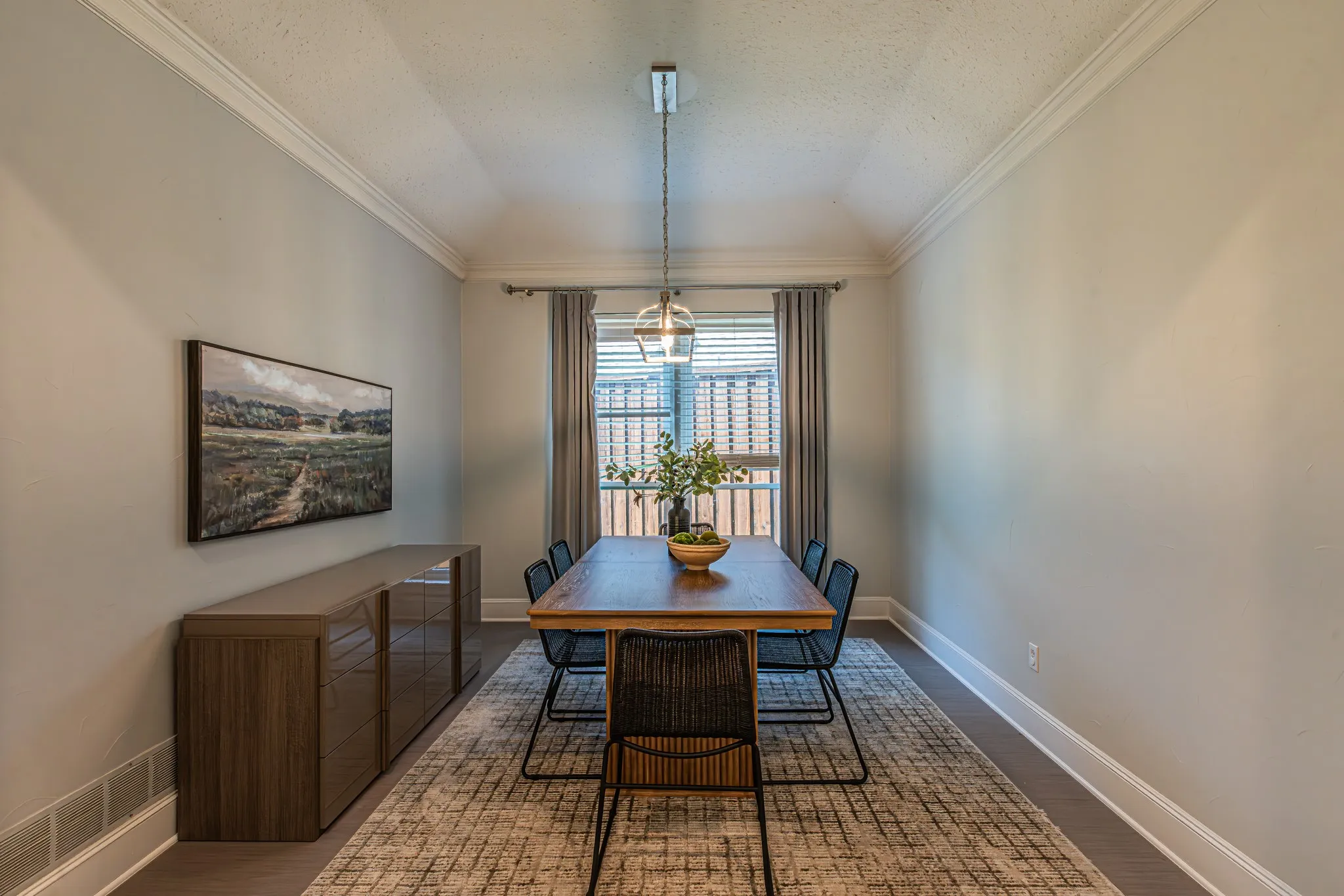 Dining area featuring crown molding, neutral wall tones, wood-finish flooring, and a contemporary pendant light fixture