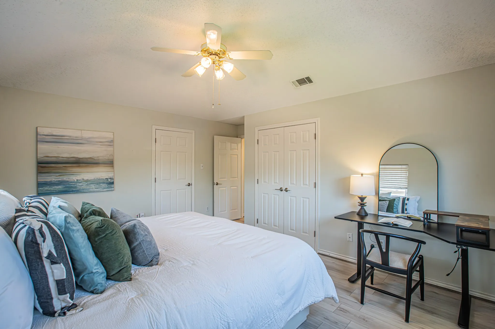Light-toned wood-finish flooring, ceiling fan with light fixture, and neutral wall paint