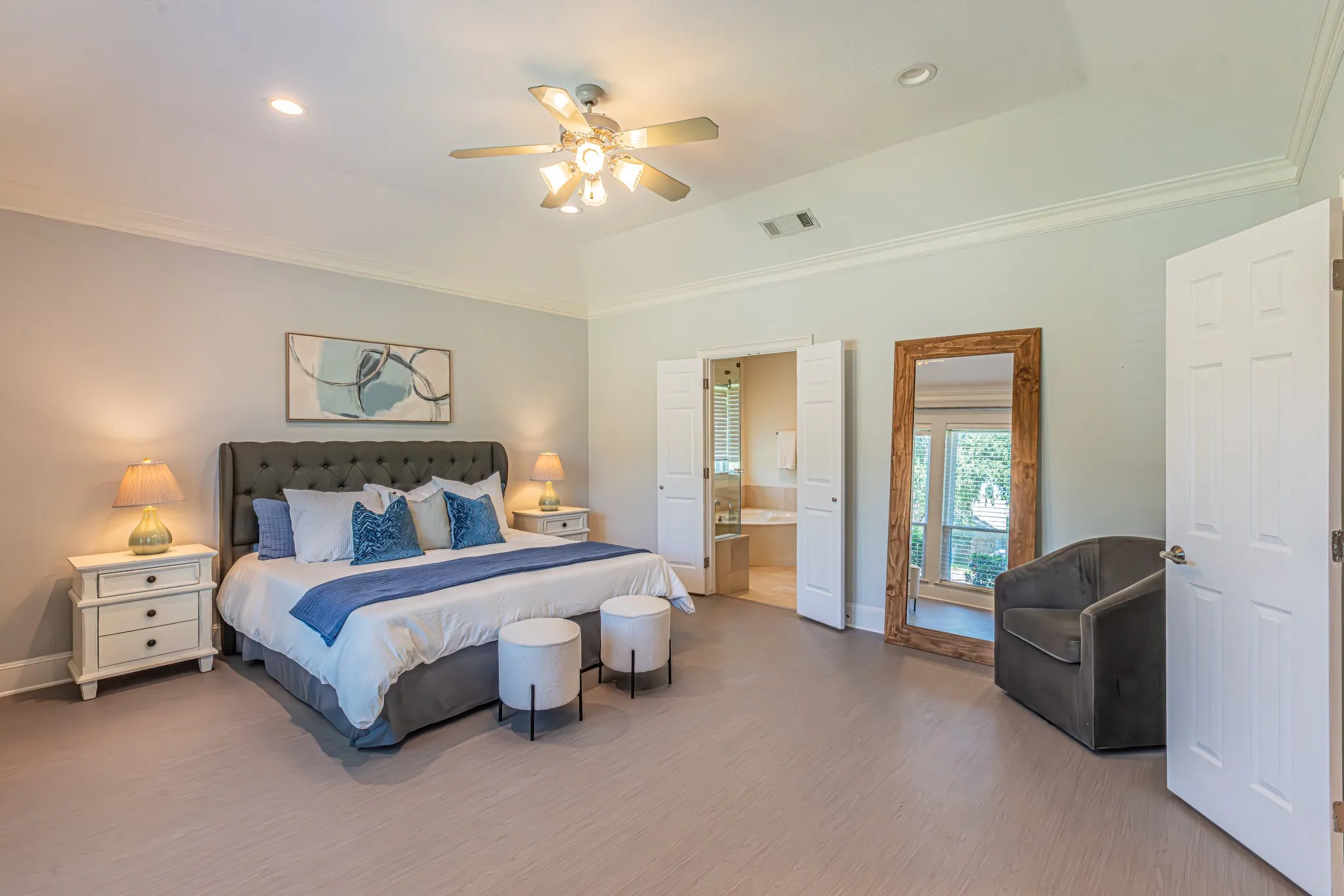 Vaulted ceiling with crown molding, recessed lighting, ceiling fan, wood-finish flooring, and double doors opening to a bathroom