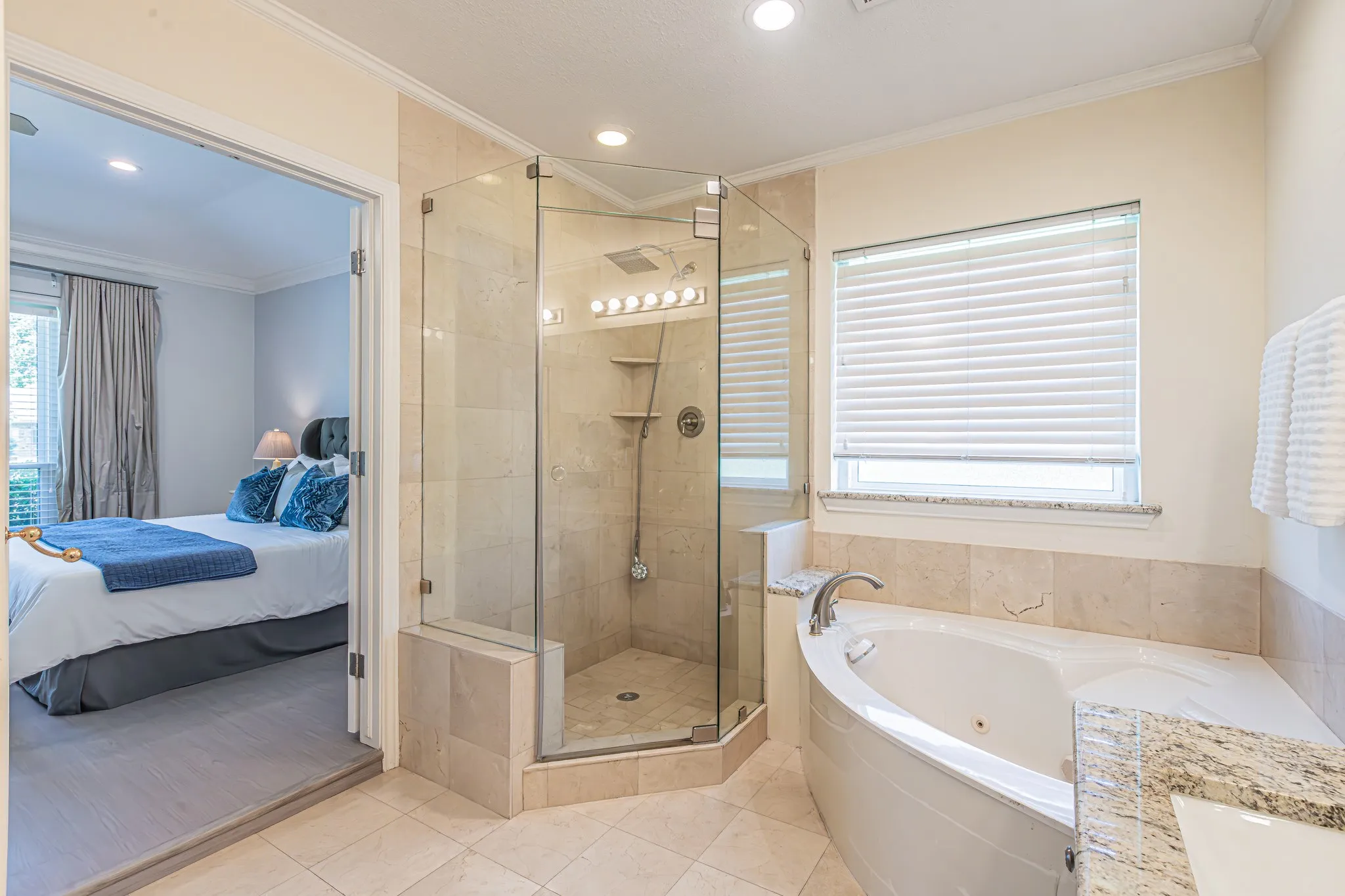 Corner glass-enclosed shower with tiled walls, separate jetted tub with granite surround, and tiled flooring