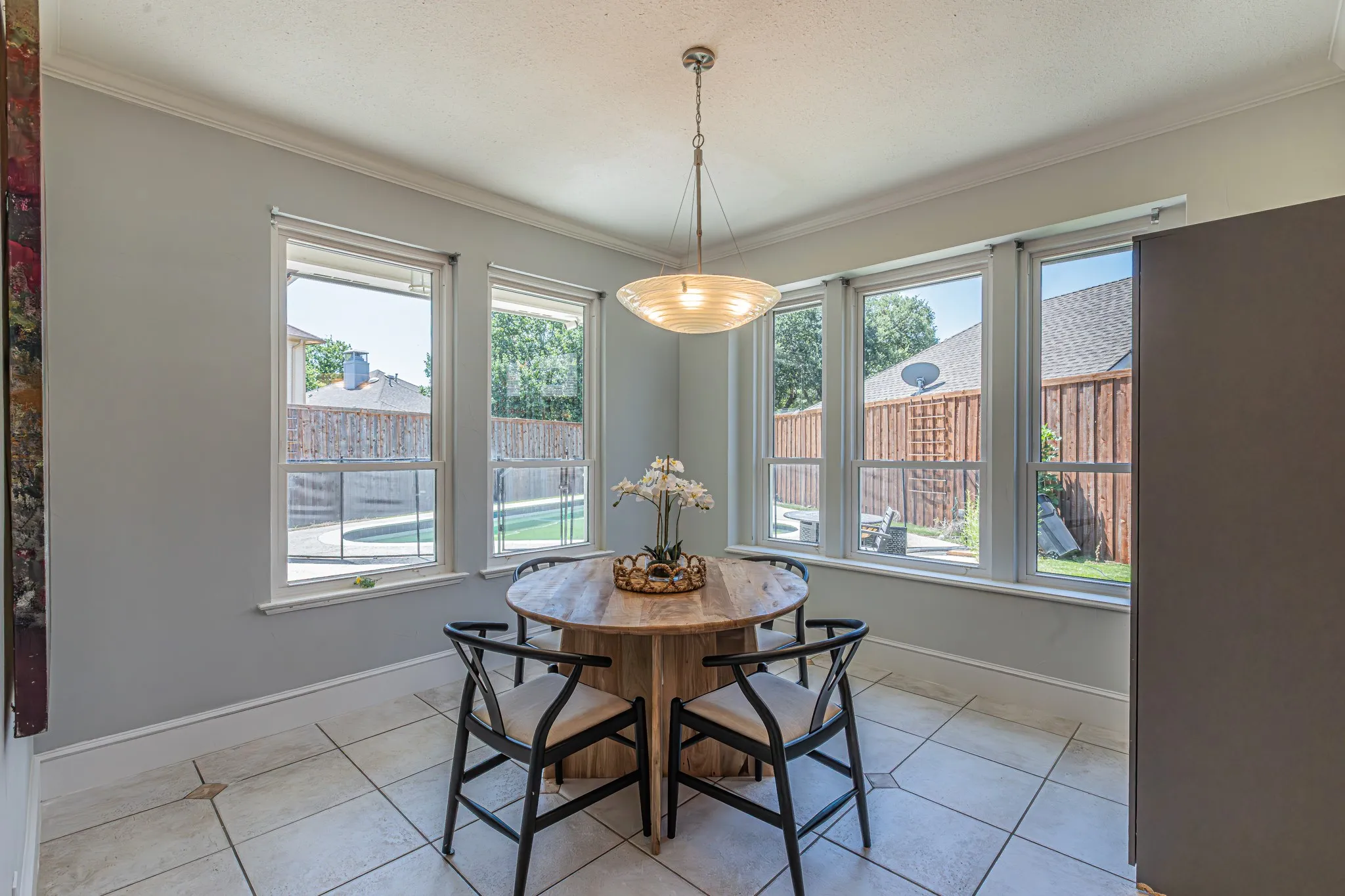 Recessed window bay with multiple windows, crown molding, a hanging pendant light fixture, and tile flooring
