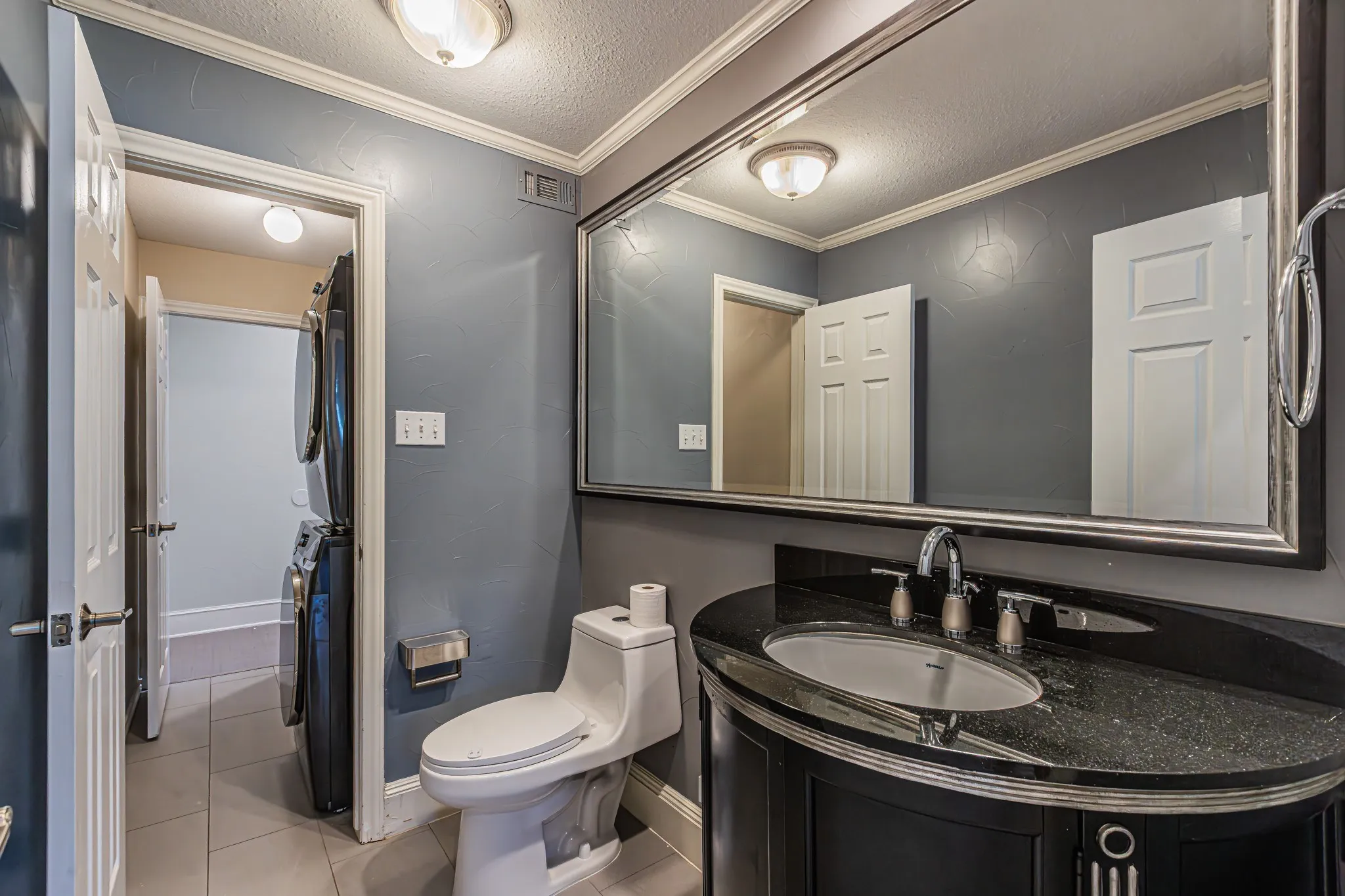 Vanity with an integrated oval sink, dark countertop, and chrome faucet