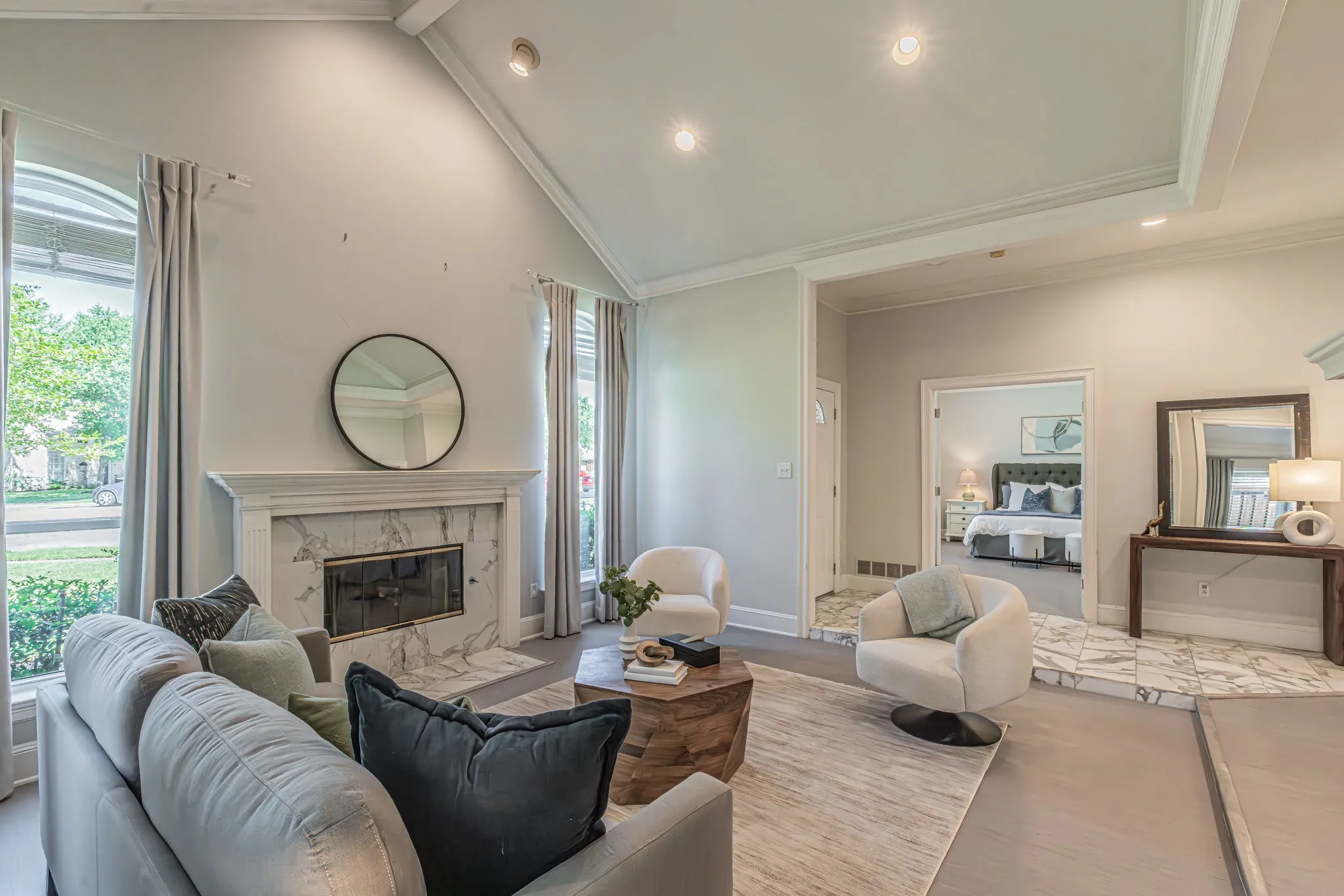 Vaulted ceiling with recessed lighting, floor-to-ceiling windows, fireplace with a marble-style surround, wood-finish flooring, and white trim throughout