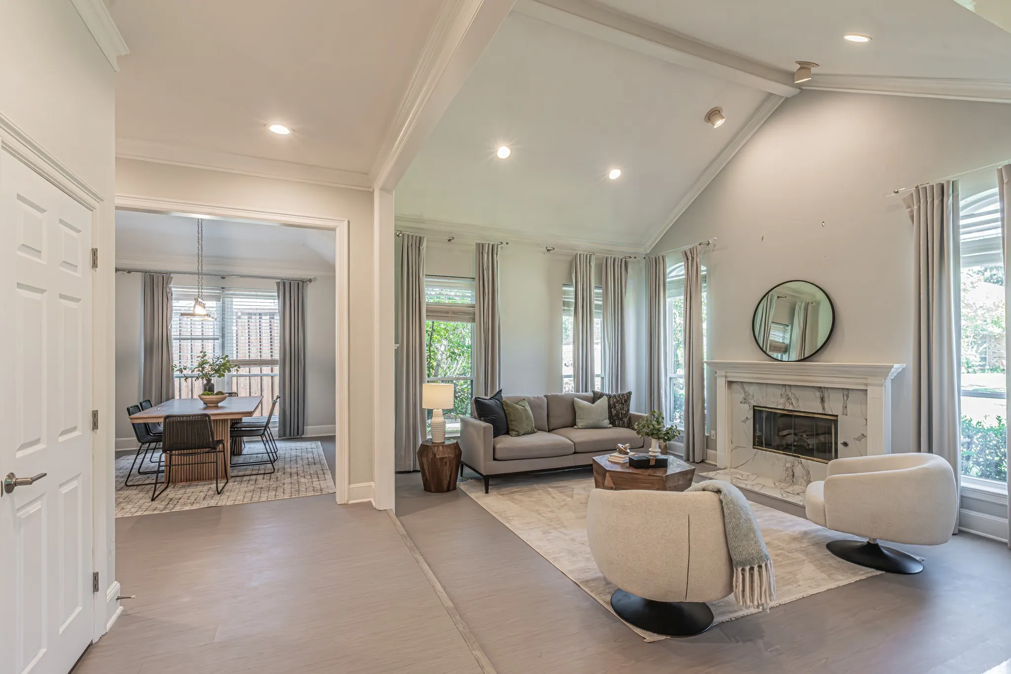 Vaulted ceiling living area with a fireplace featuring a stone surround, recessed lighting, and large windows