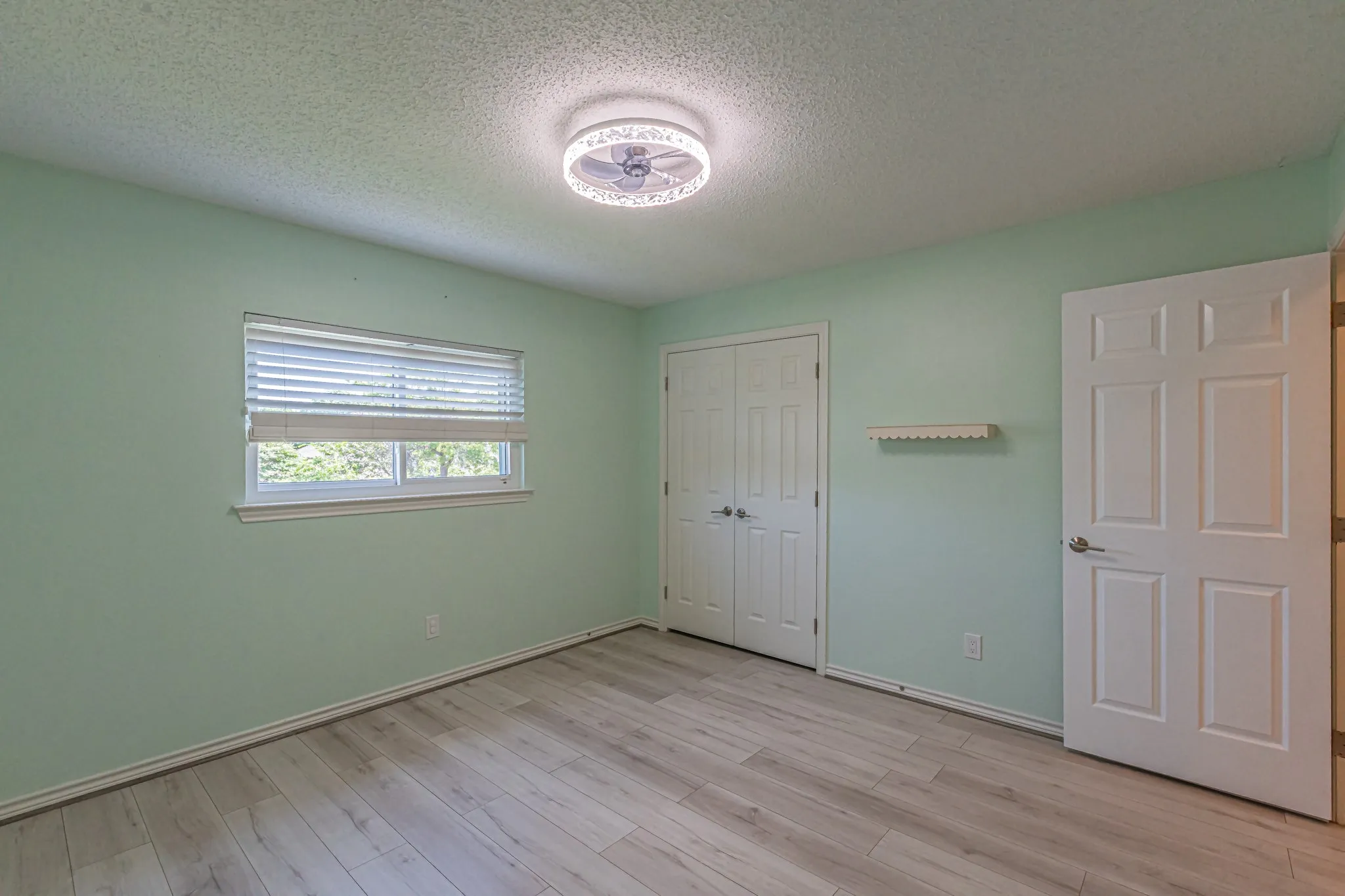Wood-finish flooring, white window blinds, bi-fold closet doors, and a ceiling-mounted light fixture