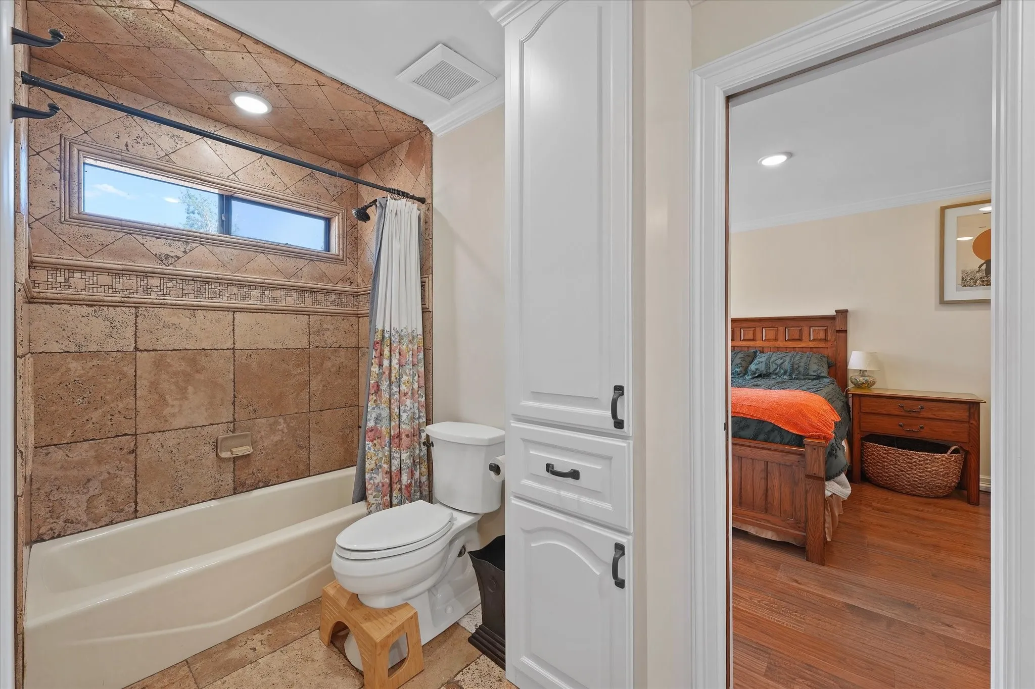 Upstairs bath with a tub/shower combination and custom travertine tilework.