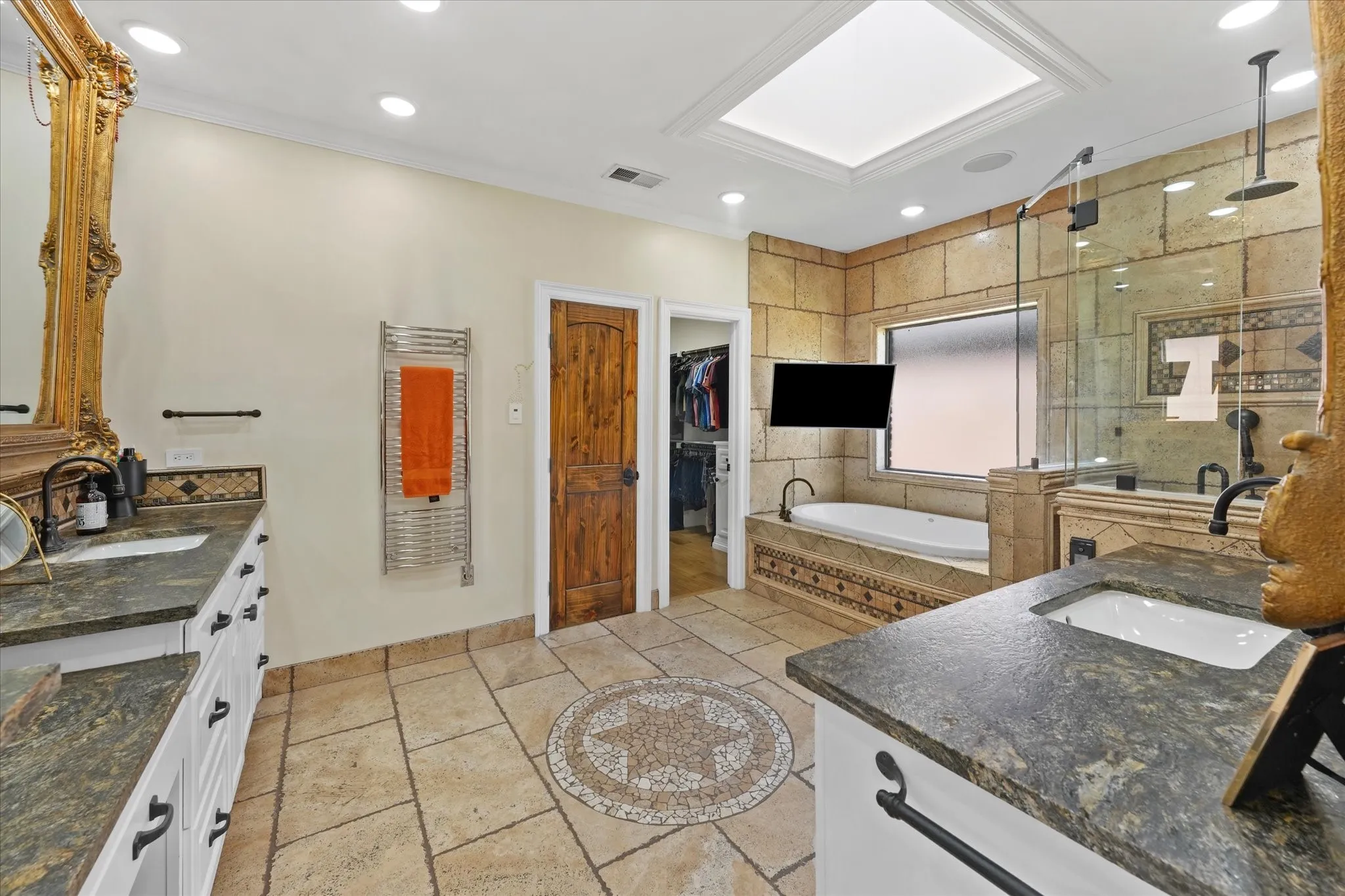 Heated travertine floors, dual vanities and a towel warmer add comfort to the primary bath.