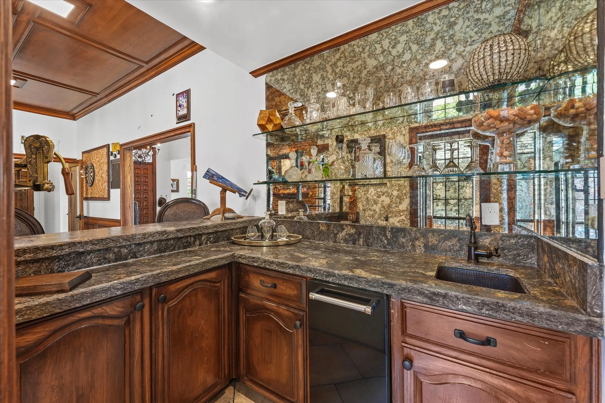 Custom wet bar with a smoked mirror, floating glass shelves, ice maker and a hammered copper sink.