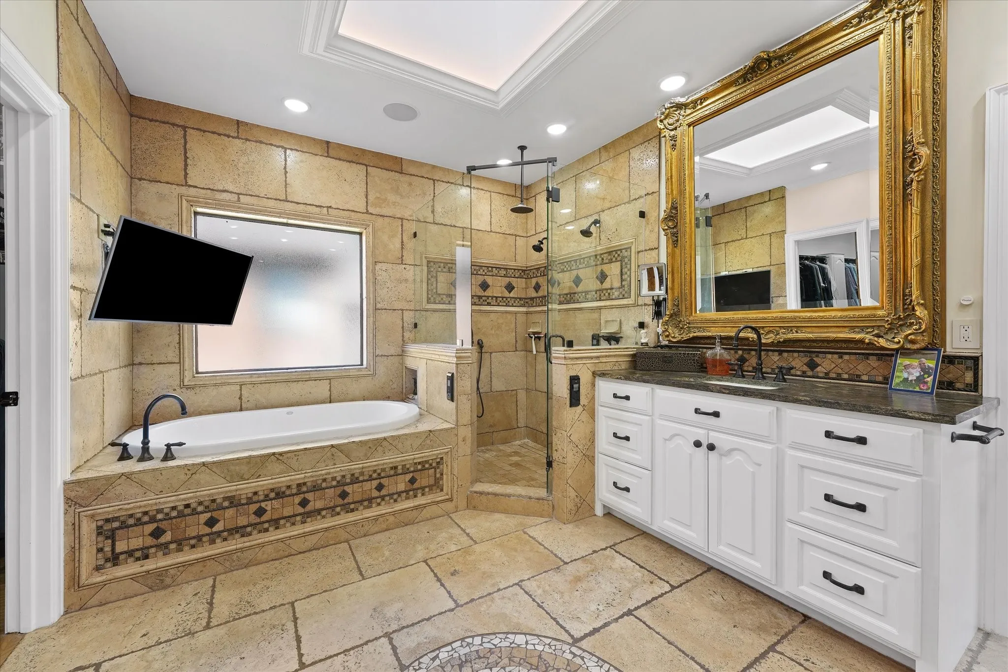 Skylit primary bath with a deep soaking tub, Kohler digitally controlled shower and large television.