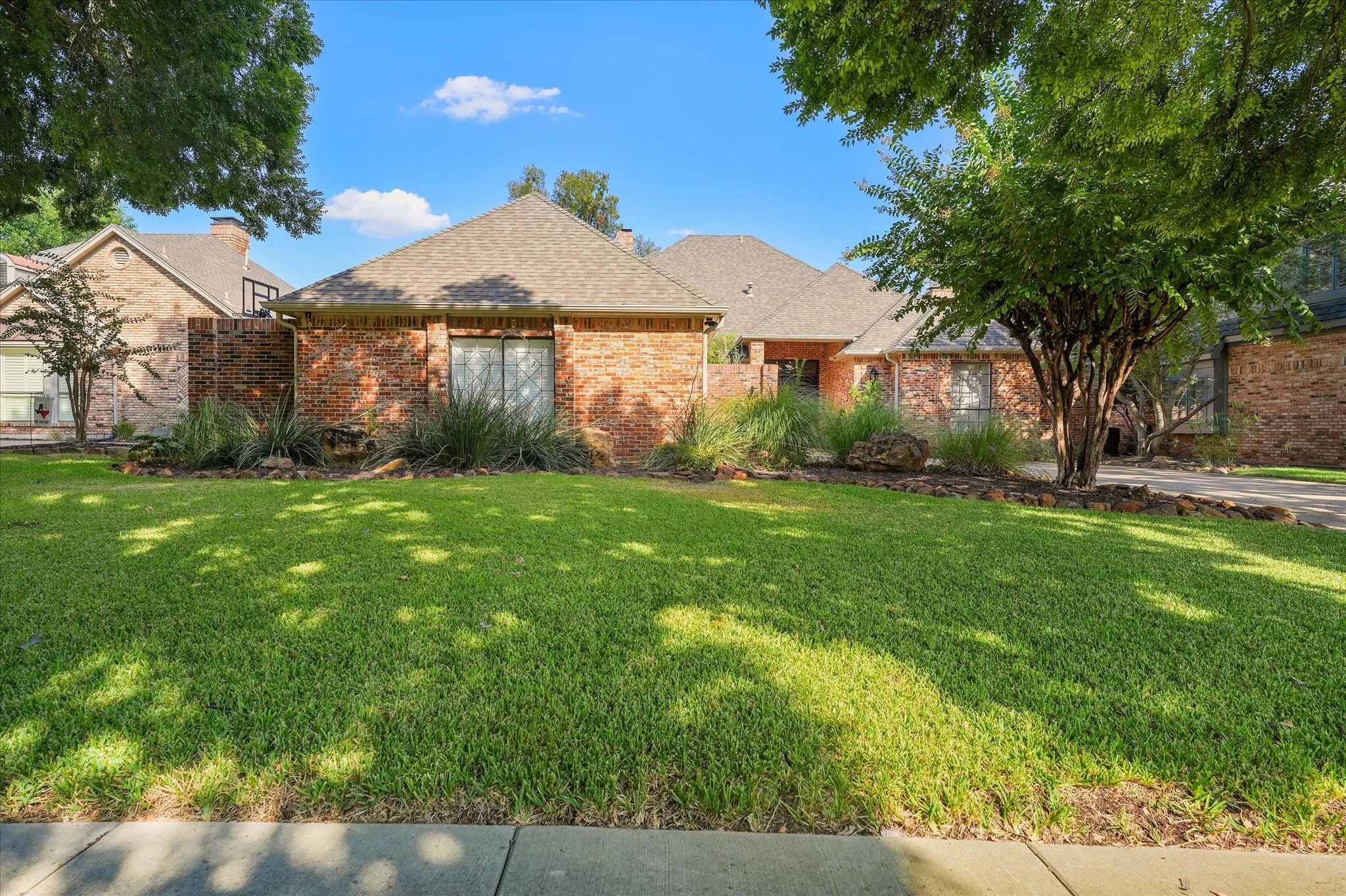 Daylight view of the brick exterior, mature trees and established landscaping.