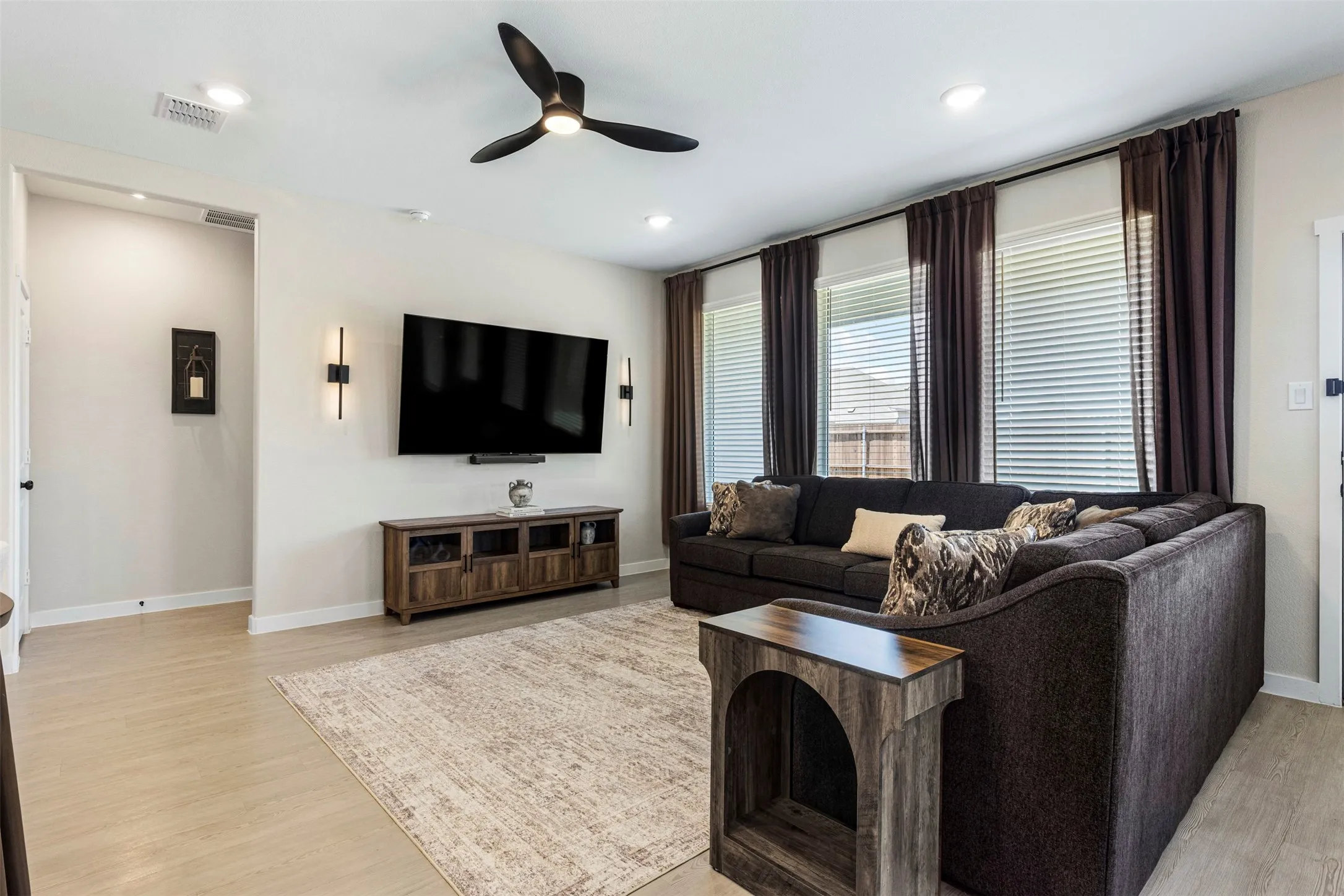 Recessed lighting, ceiling fan, wood-finish flooring, multiple windows, and wall sconces