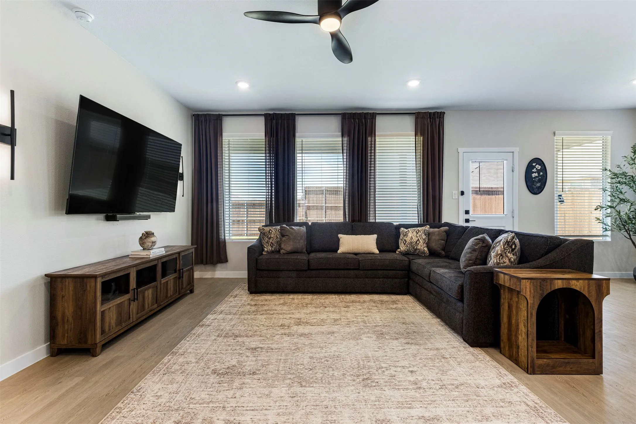 Recessed lighting, ceiling fan, wood-finish flooring, multiple windows with blinds, and a white paneled door