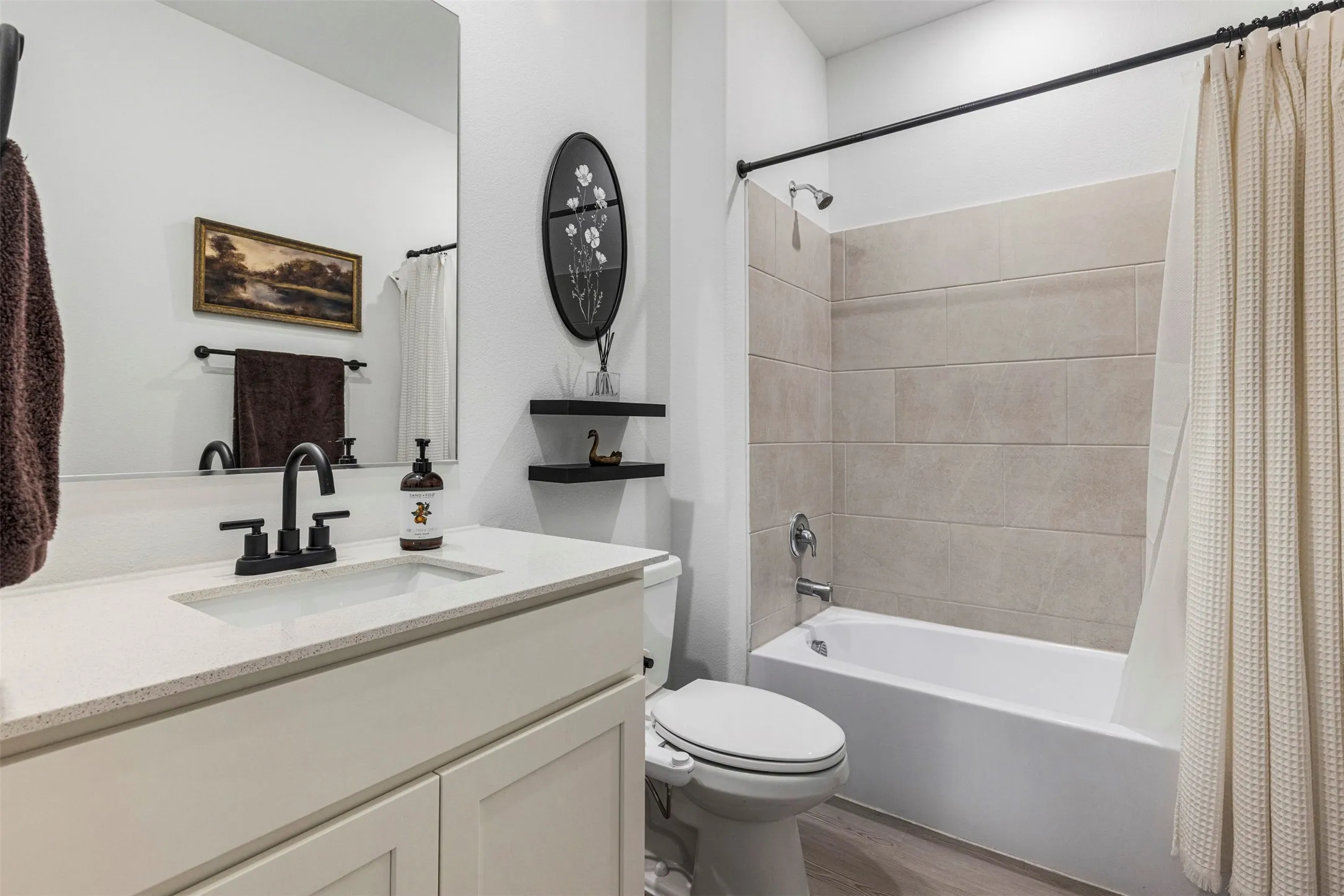 White vanity with a light-toned countertop and matte black fixtures
