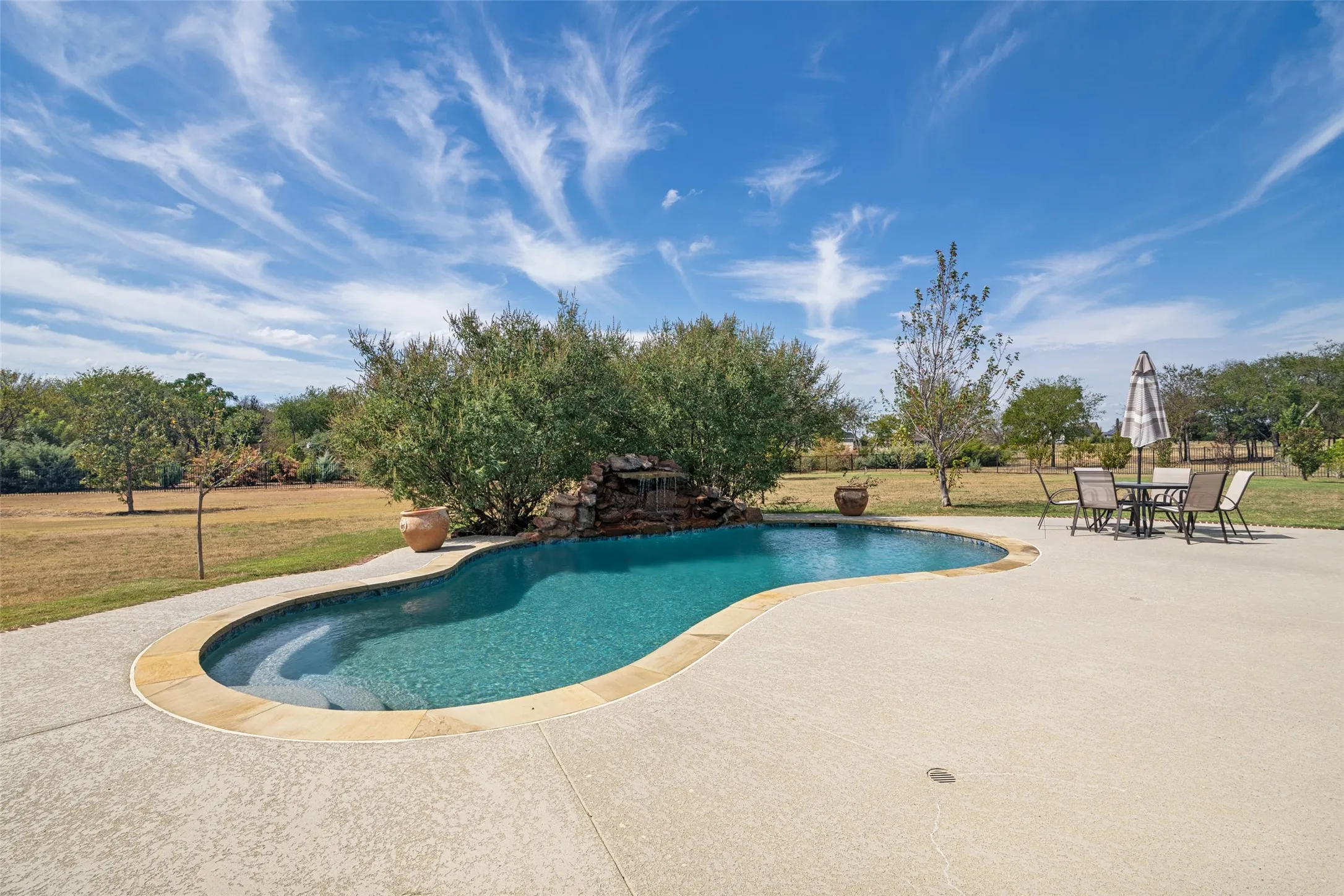 Pool with lots of decking and beautiful waterfall