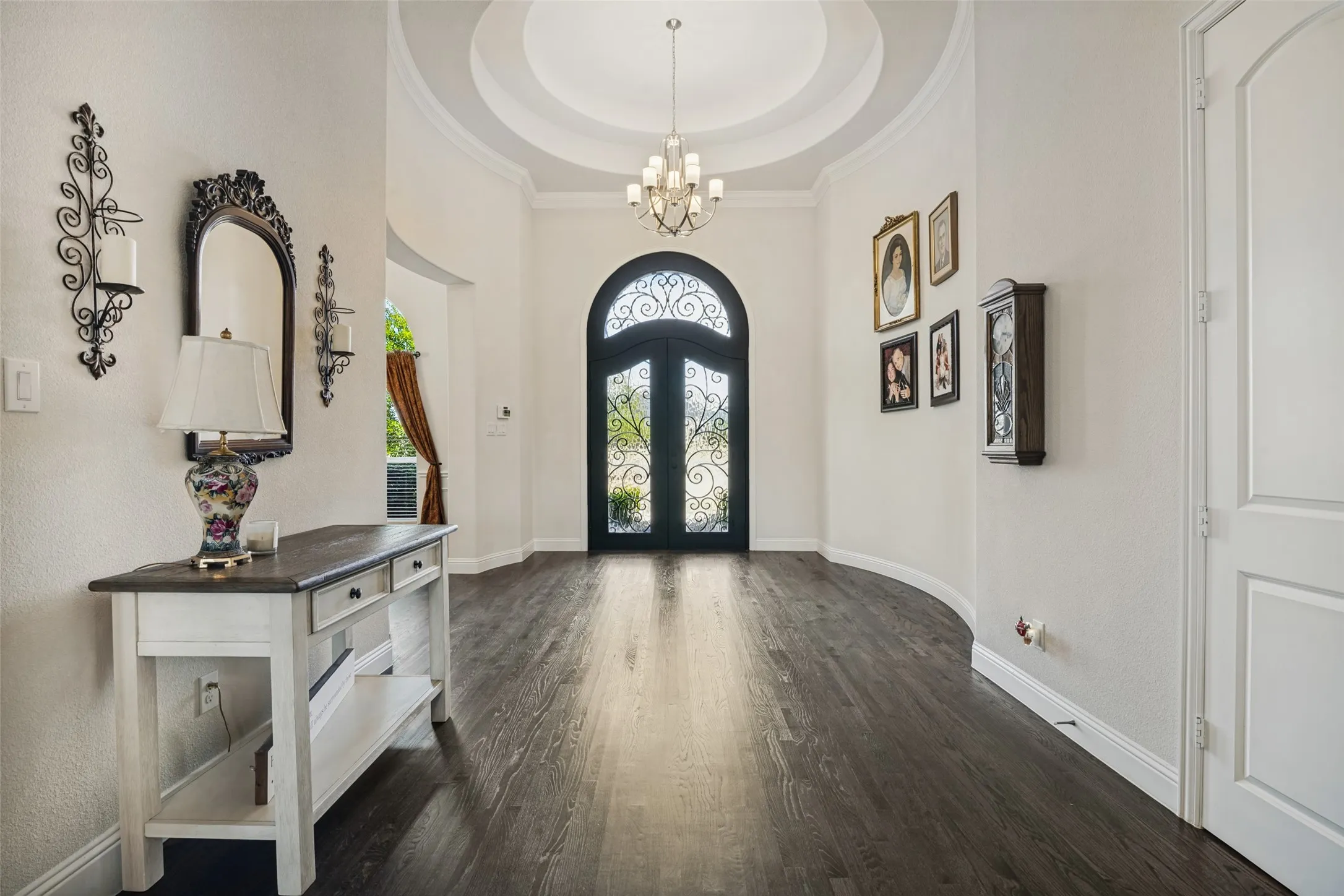 Elegant entry with iron doors, beautiful chandelier and hard wood floors.