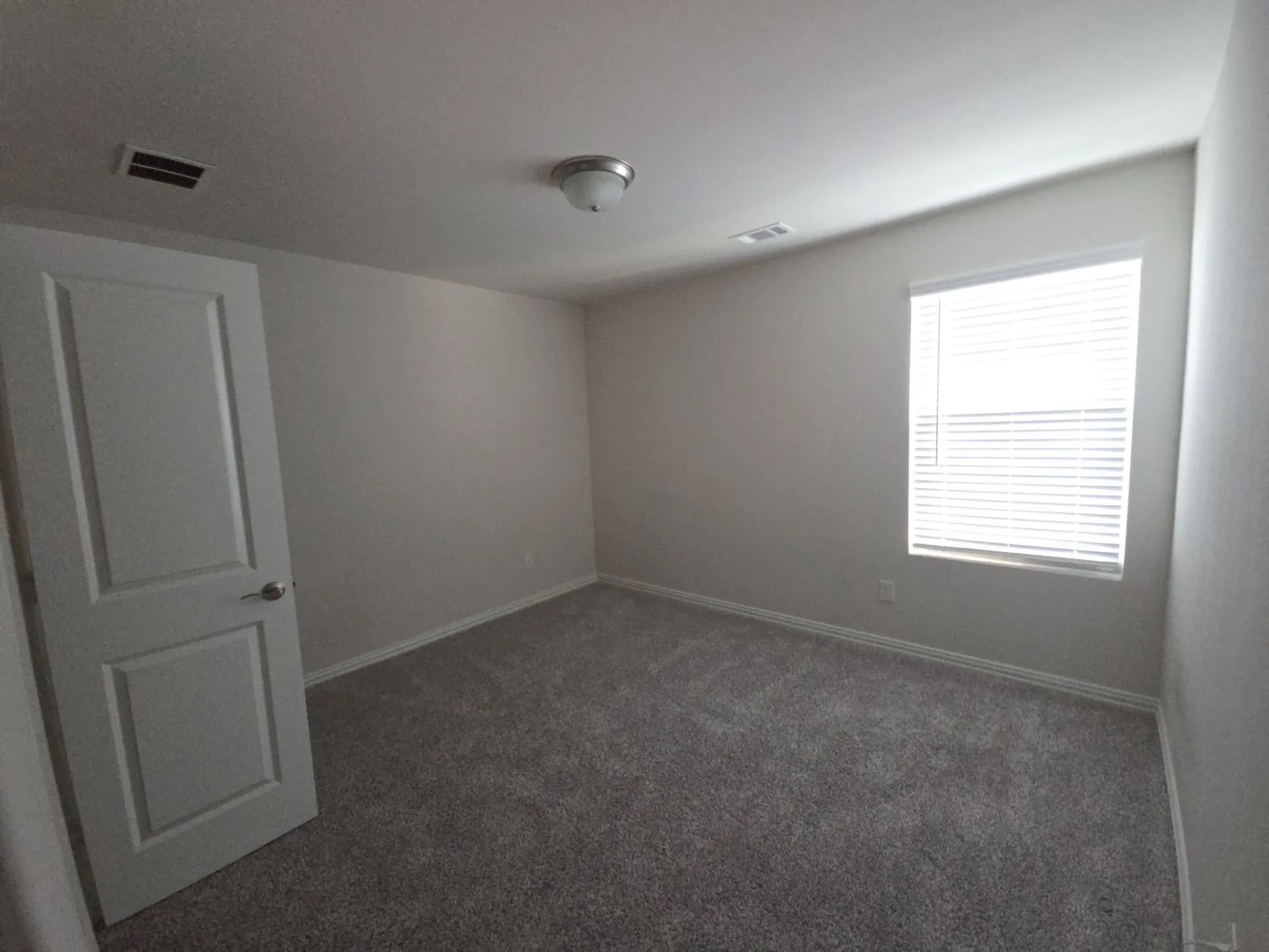 Neutral wall paint, gray carpet flooring, white trim, window with blinds, and flush-mount ceiling light