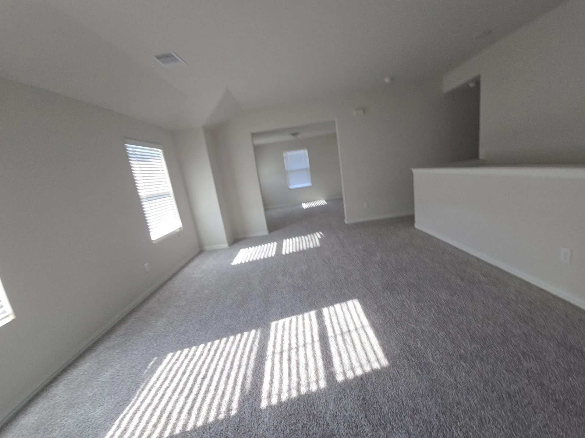 Expansive carpeted area with multiple windows featuring horizontal blinds