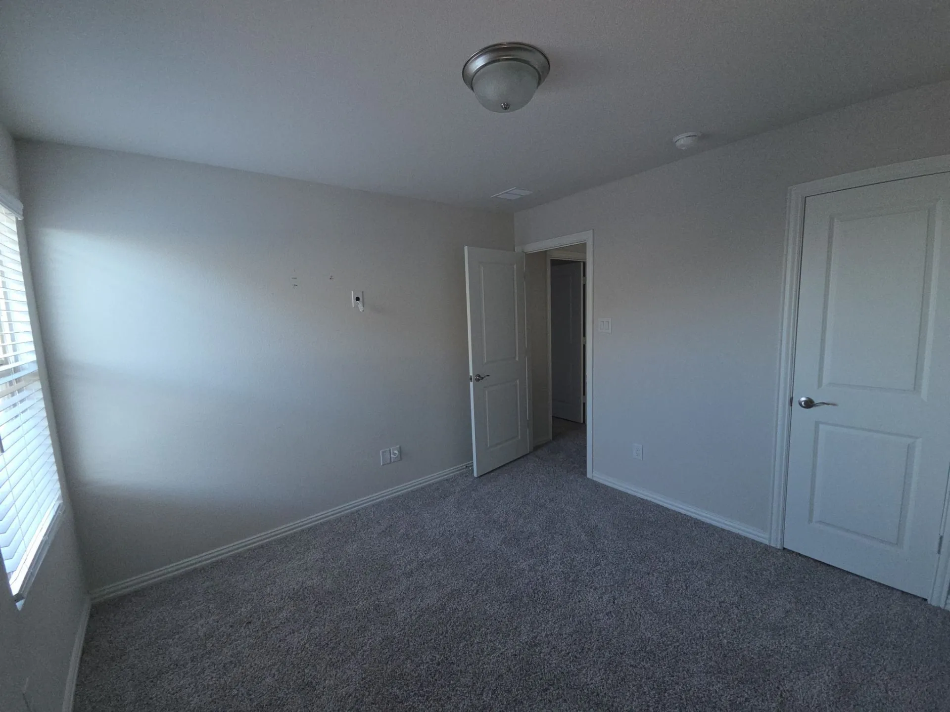 Neutral wall paint, gray carpet, flush mount ceiling light fixture, white trim, and a window with blinds
