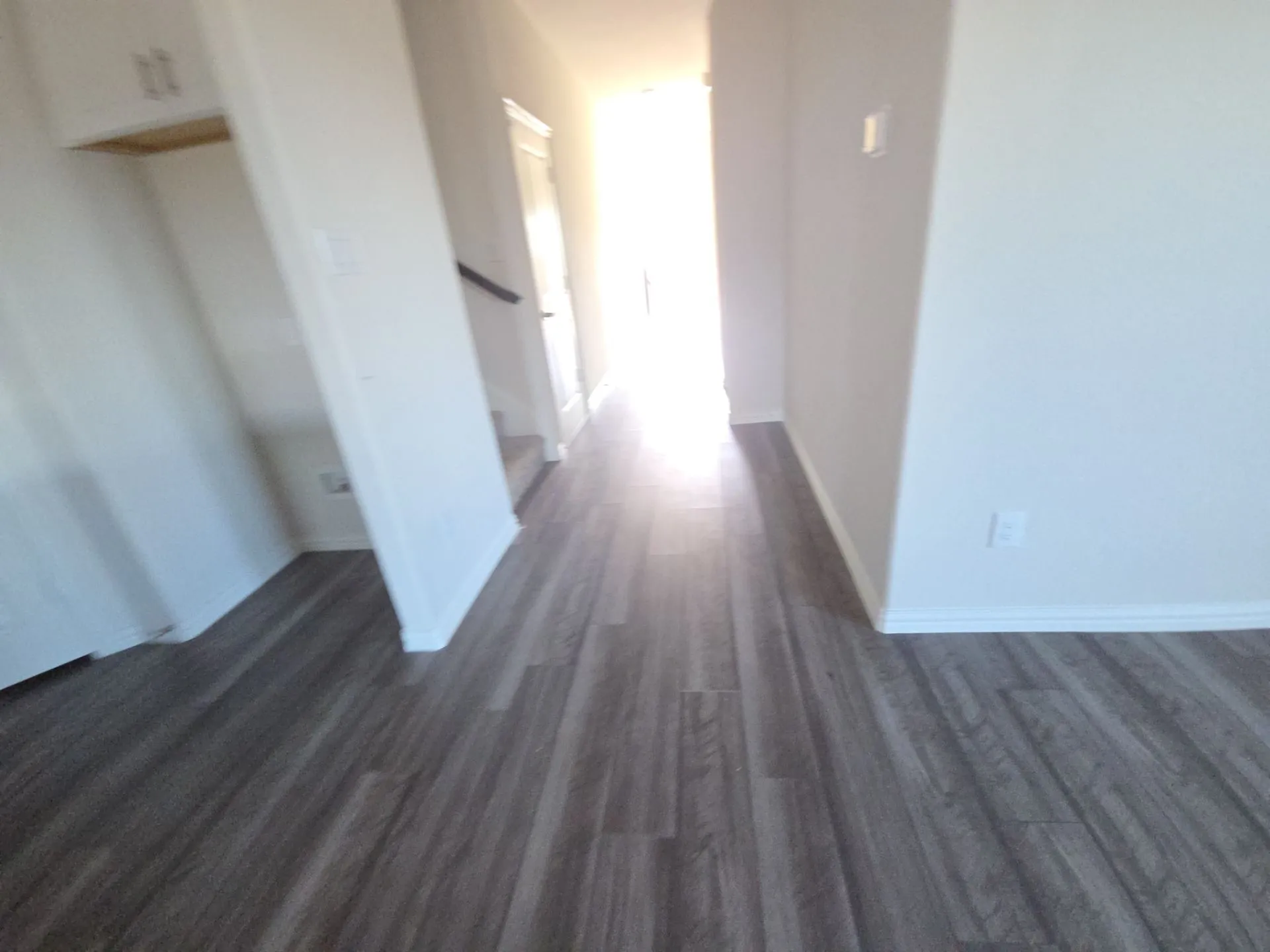 Wood-finish flooring throughout, white walls, and built-in cabinetry with a wood shelf