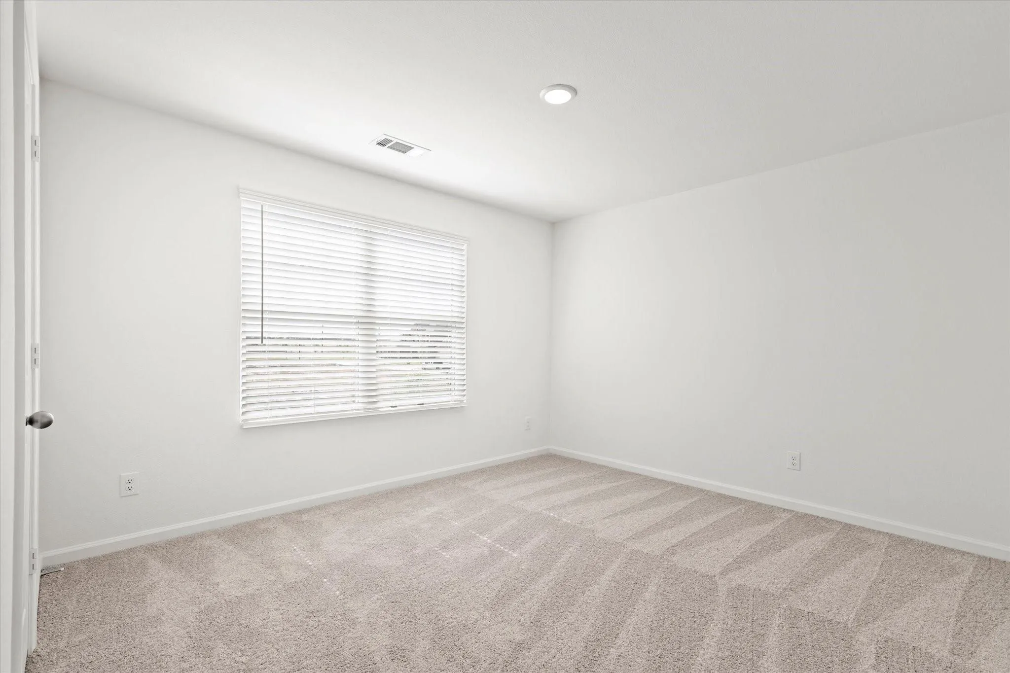 Neutral-toned carpeting, white painted walls, and a recessed ceiling light