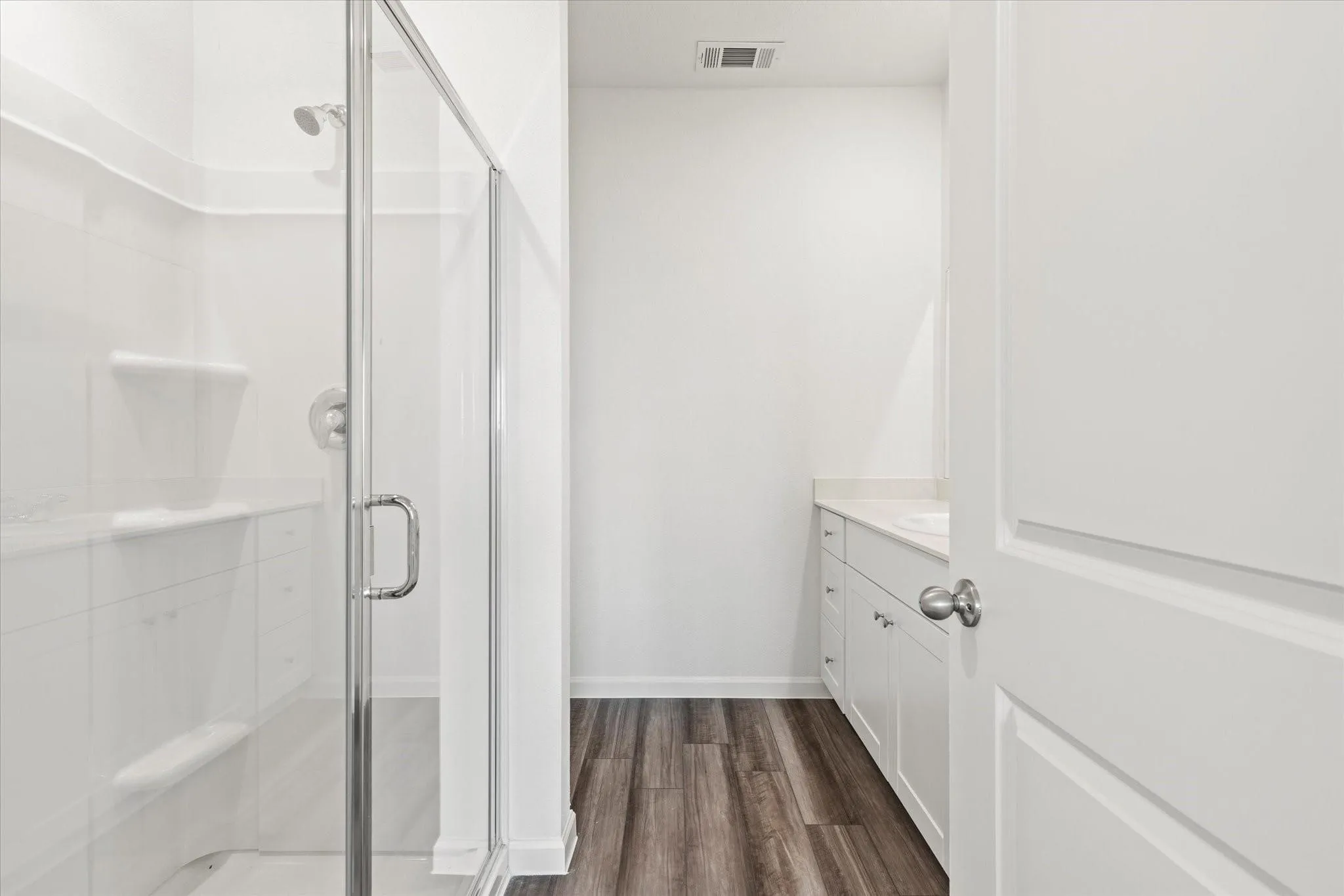 Glass-enclosed shower with built-in shelving and bench