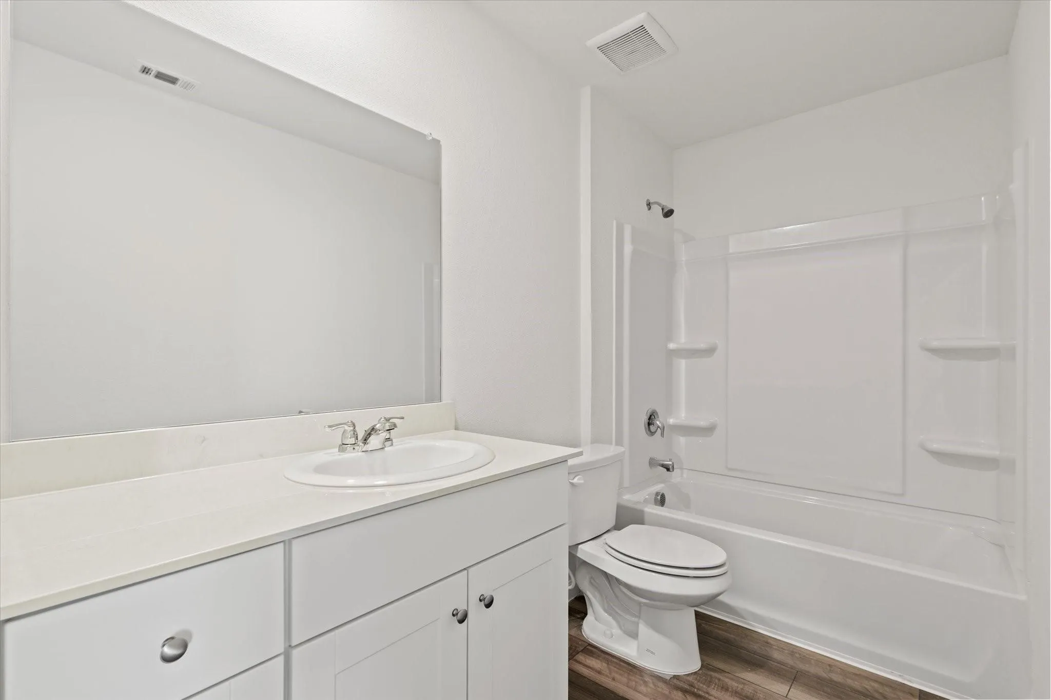 White vanity with integrated sink, polished chrome faucet, and expansive mirror