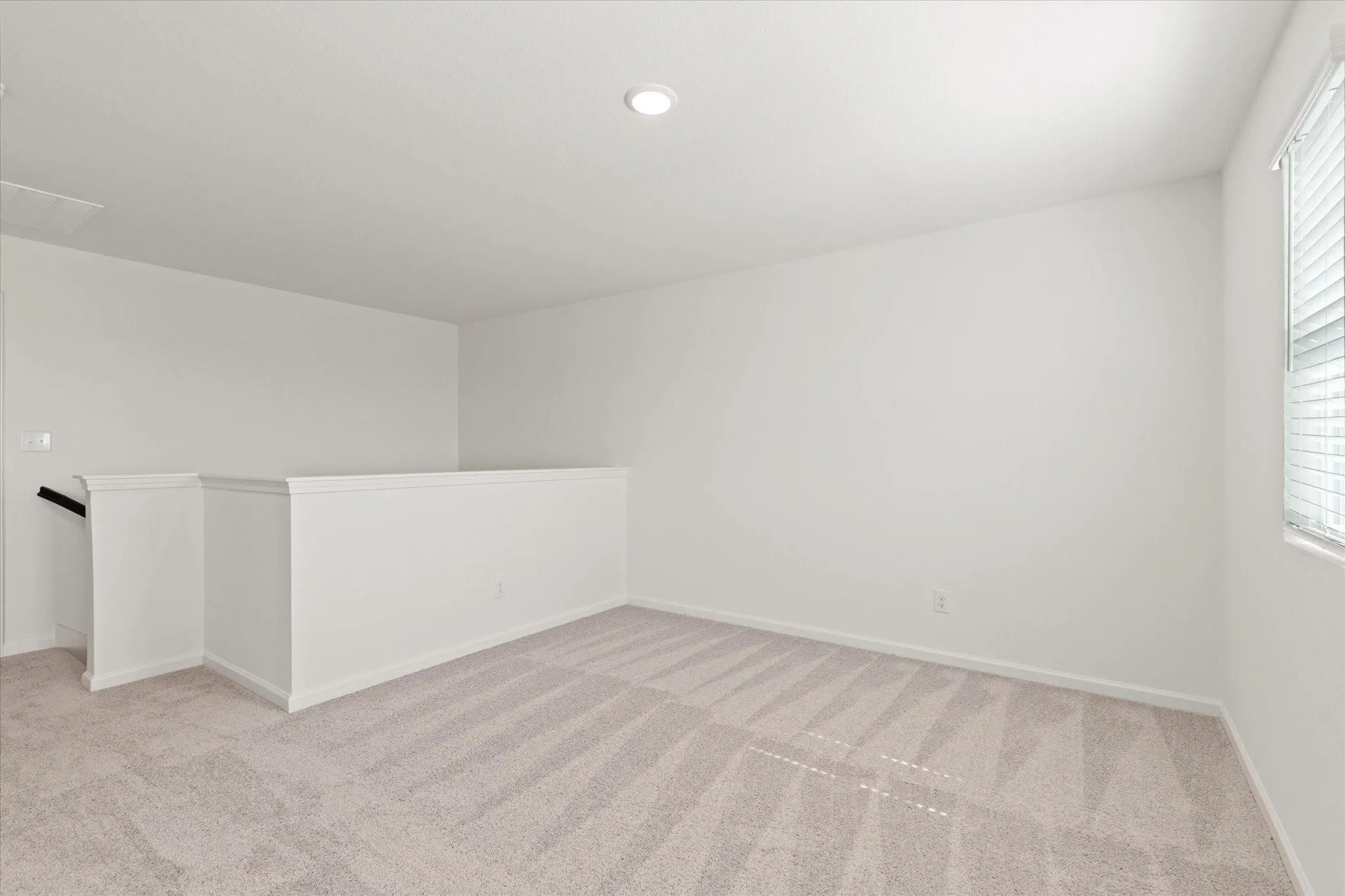 Upstairs Living Area; Neutral-toned carpeting, white walls, and a single window with blinds