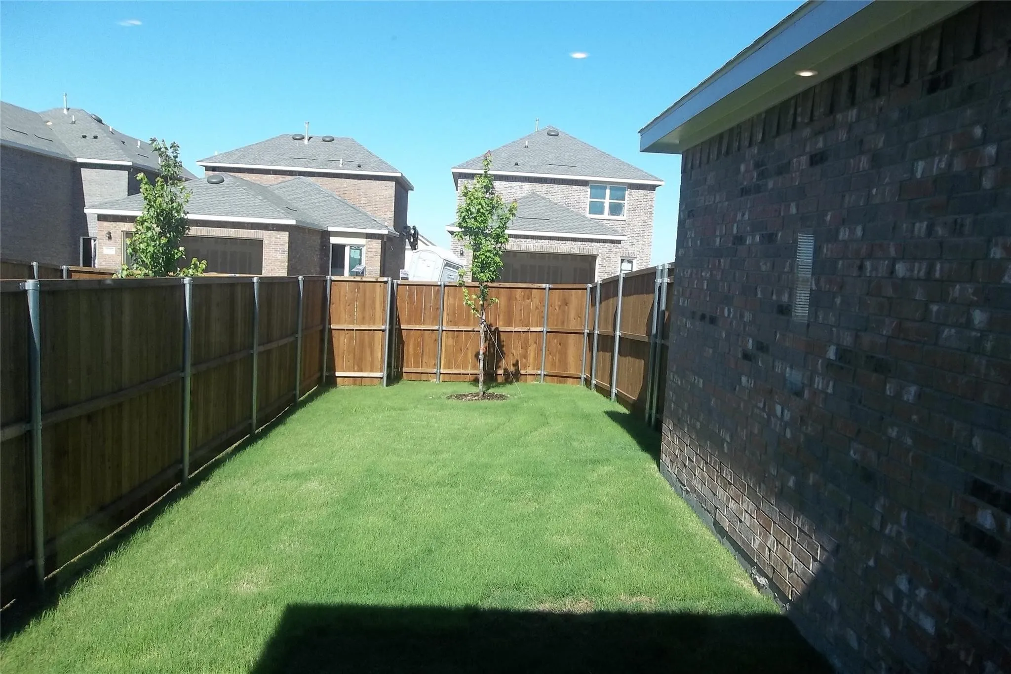 Enclosed backyard featuring a manicured lawn, established privacy fencing, and brick exterior