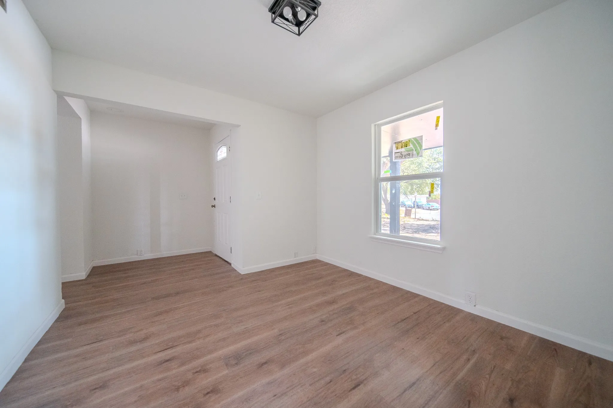 Wood-finish flooring, white walls, and a recessed entry door with a frosted glass panel