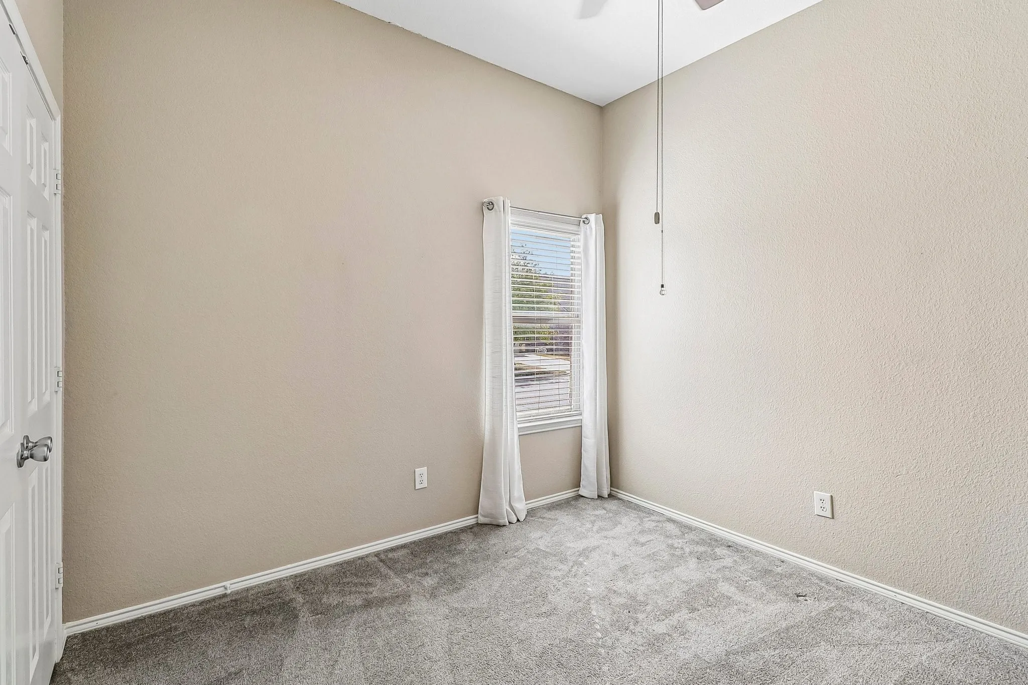 Vaulted ceiling with an integrated ceiling fan, neutral wall paint, window with blinds, and gray carpet flooring